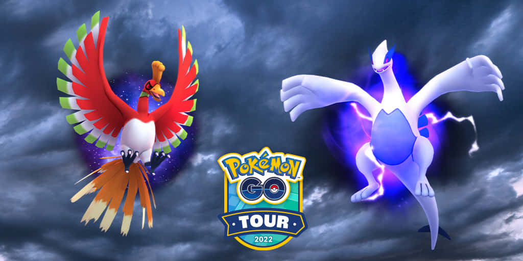 動漫 桌布 壁紙 — 兩隻傳說中的寶可夢，Ho-Oh 和 Lugia，在暴風雨的天空下戲劇性地翱翔，下方中央是 Pokémon GO Tour 2022 標誌。