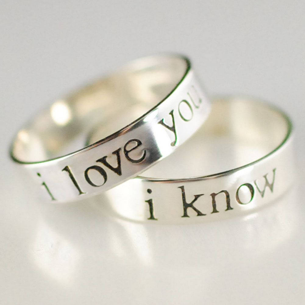 Wedding Rings 桌布 壁紙 — 兩隻刻有「i love you」和「i know」的銀戒指，以極簡構圖放置在柔軟的白色表面上。