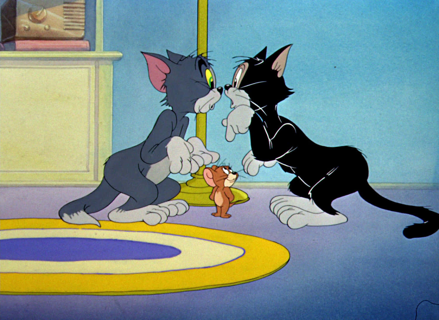Tom And Jerry Funny 桌布 壁紙 — 兩隻卡通貓在房間內對峙，一隻小老鼠站在牠們之間的地毯上。