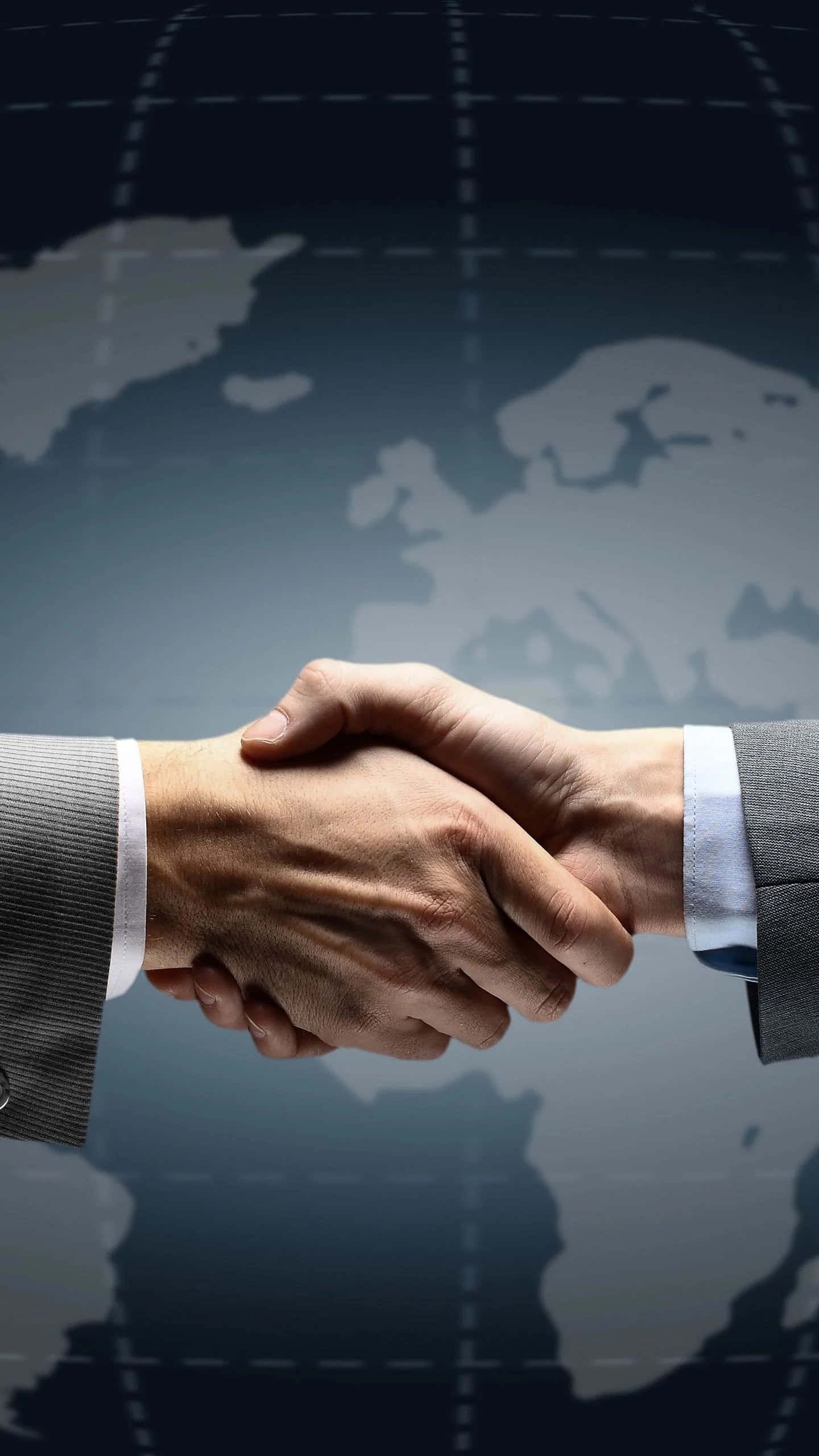 hands 桌布 壁紙 — 兩隻商業手在模糊的世界地圖背景下堅定握手，象徵全球合作夥伴關係。