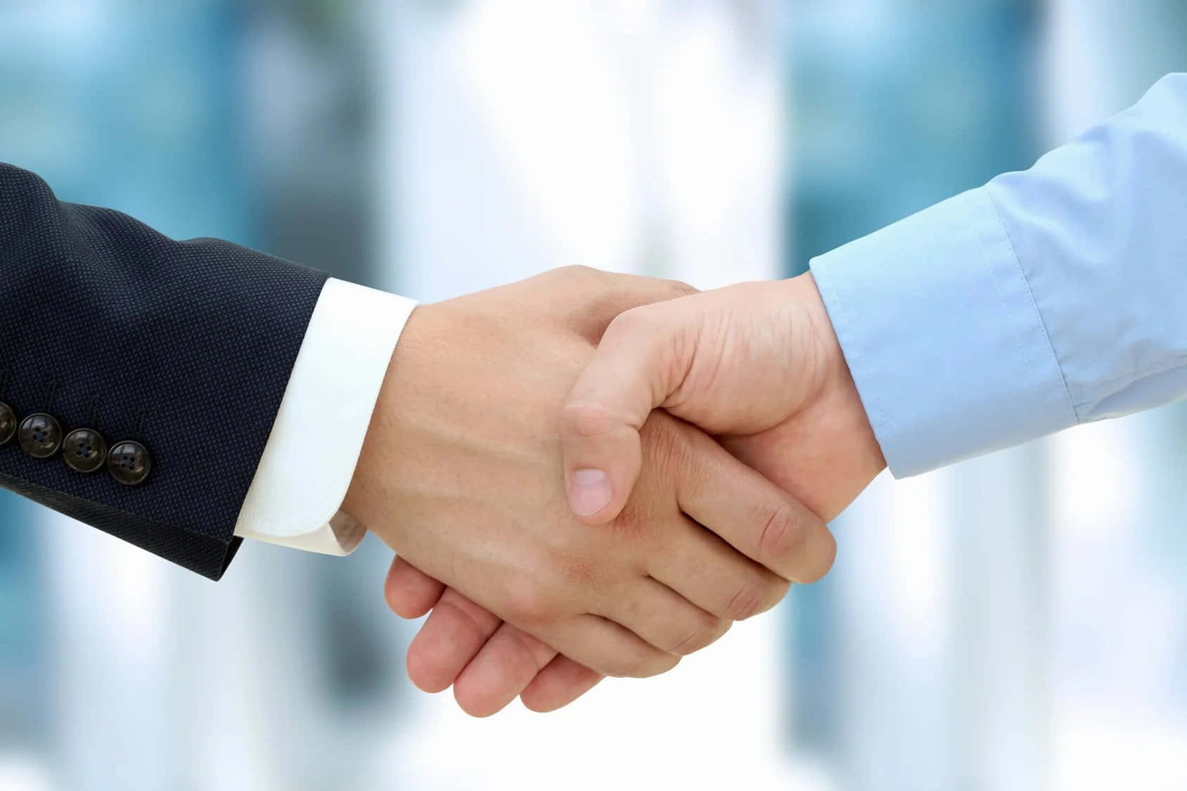 hands 桌布 壁紙 — 兩隻商業手在模糊的企業背景下緊緊握在一起，進行專業的握手。