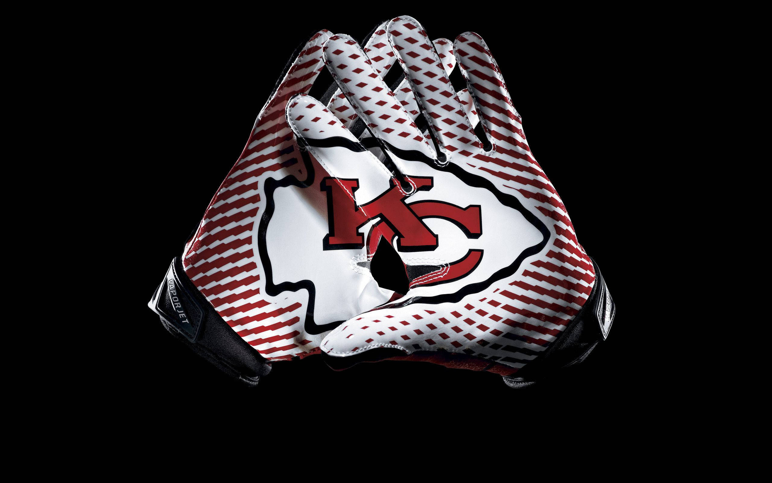 Kc Chiefs 桌布 壁紙 — 兩隻堪薩斯城酋長隊美式足球手套，帶有紅白條紋和球隊標誌，在黑色背景上緊握在一起。
