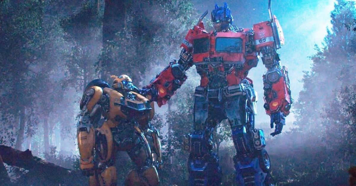 變形金剛 桌布 壁紙 — 兩隻巨型機器人柯博文和大黃蜂站在霧氣瀰漫的森林中，陽光穿過高聳的樹木照射下來。