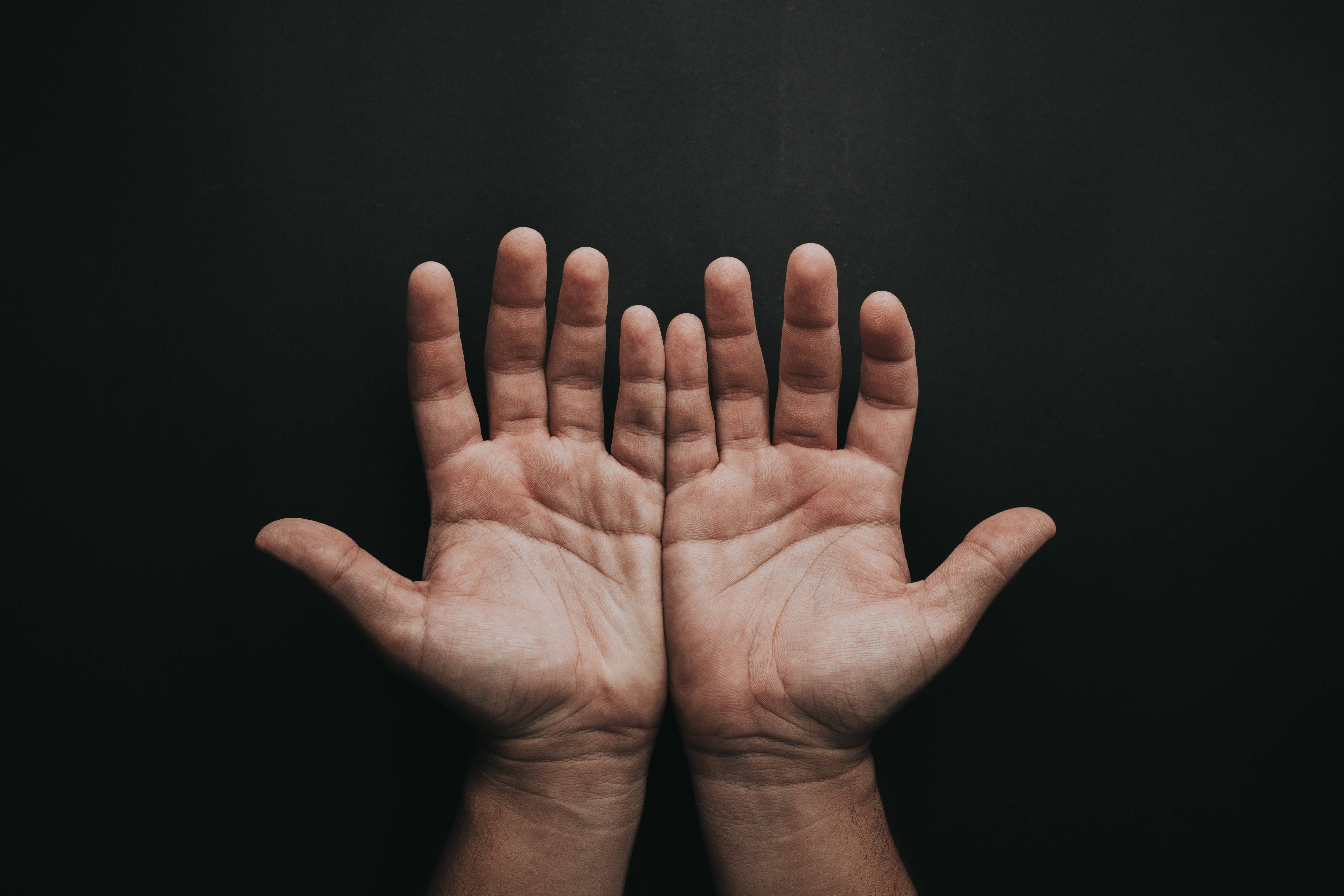 hand 桌布 壁紙 — 兩隻張開的手掌朝上，對著純黑背景，手指微微張開，在柔和光線下顯露皮膚紋理和血管。