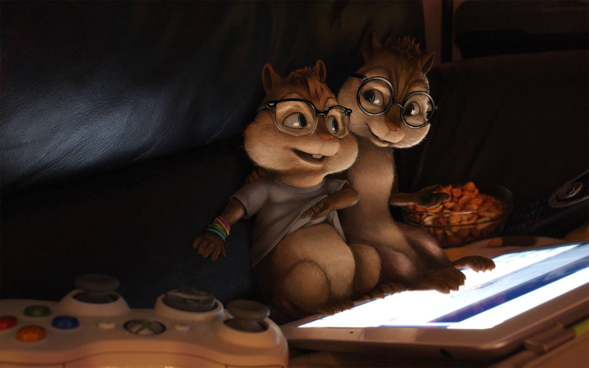 Chipmunks 桌布 壁紙 — 兩隻戴眼鏡的動畫花栗鼠舒適地坐在沙發上，在發光的平板電腦上玩遊戲，附近有一碗零食。