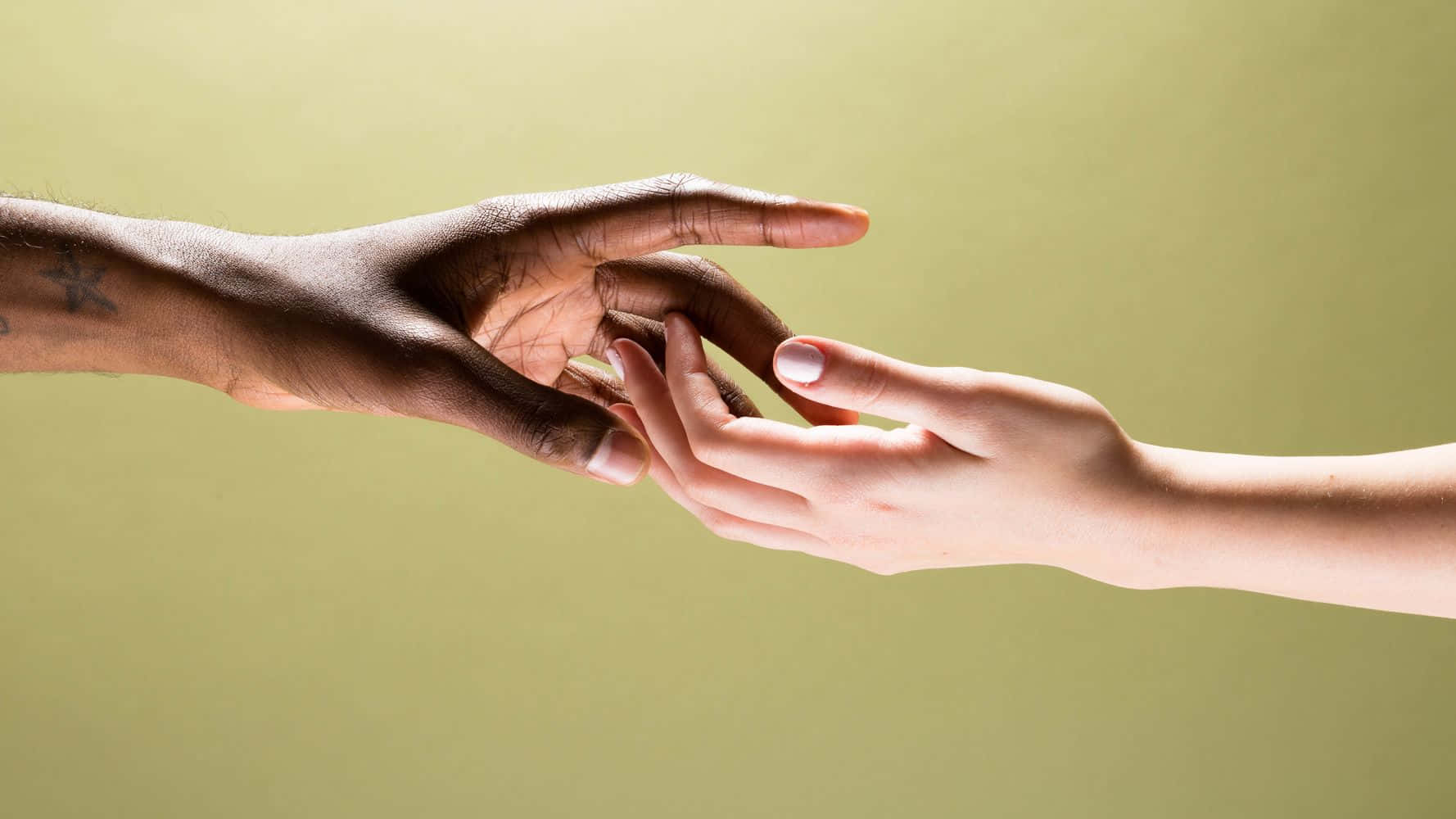 Holding Hands 桌布 壁紙 — 兩隻手，一深一淺，在柔和的橄欖色背景上互相伸向對方。