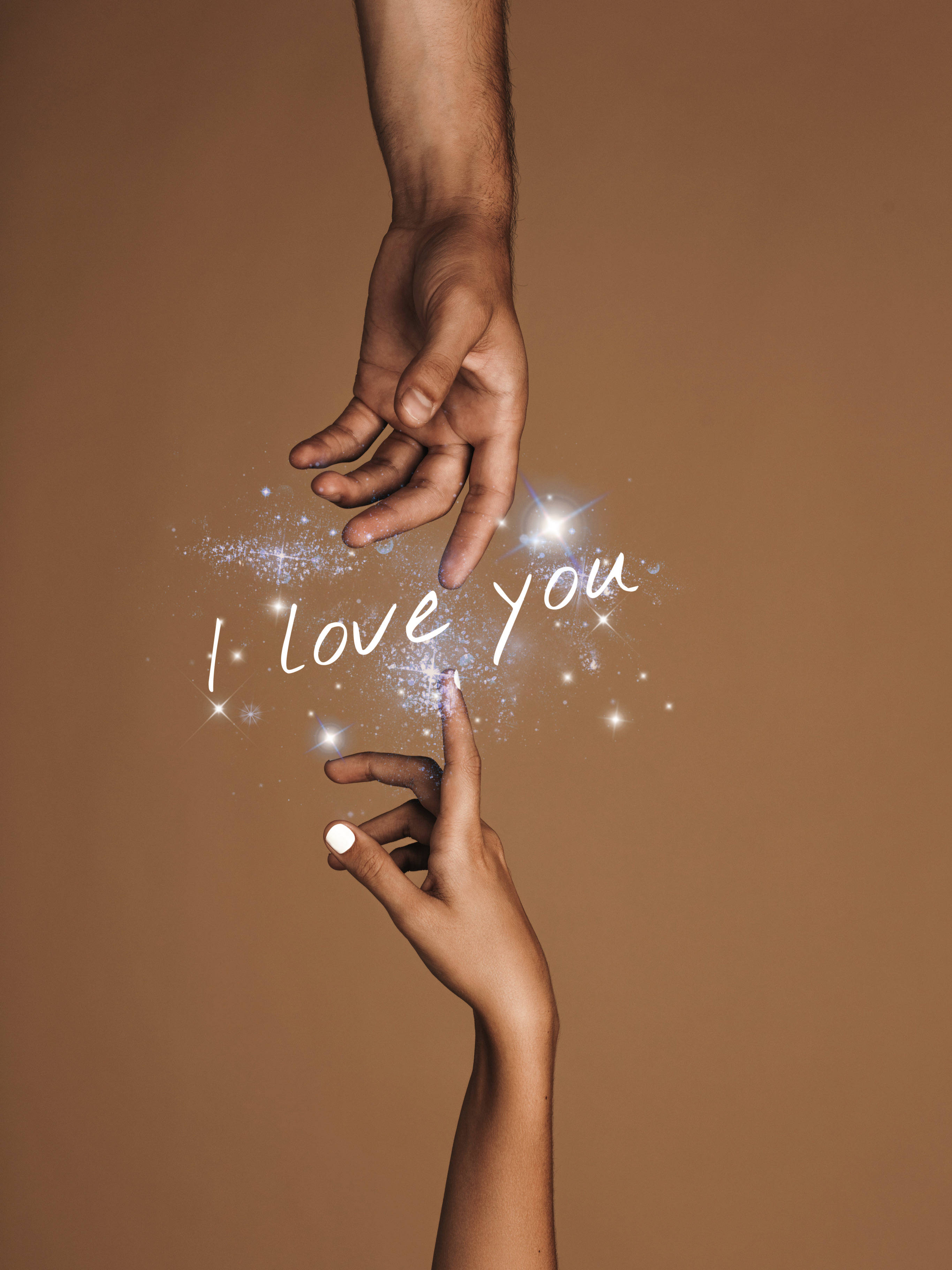 Relationship 桌布 壁紙 — 兩隻手互相伸向對方，閃爍的粒子在它們之間形成「我愛你」的字樣，背景是溫暖的棕色。