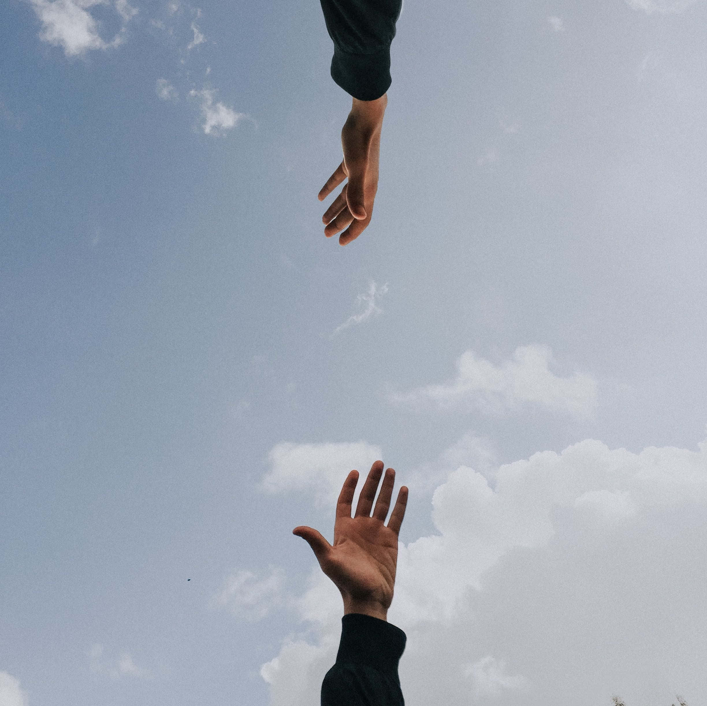 Friends 桌布 壁紙 — 兩隻手在廣闊的藍天和散落的雲朵背景下互相伸向對方。
