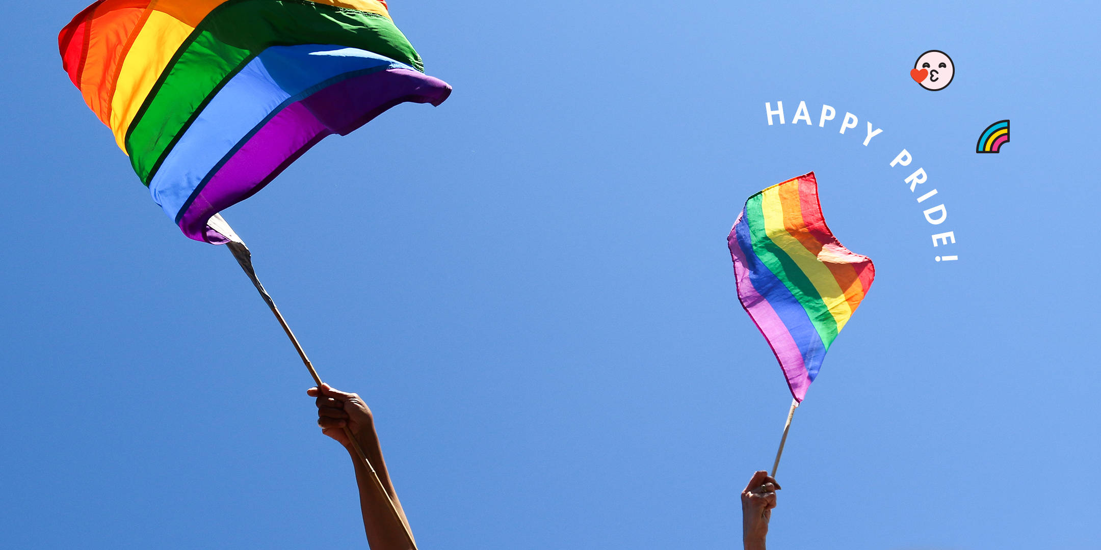 LGBT 桌布 壁紙 — 兩隻手在晴朗的藍天下揮舞彩虹驕傲旗幟，帶有「HAPPY PRIDE！」文字和表情符號。