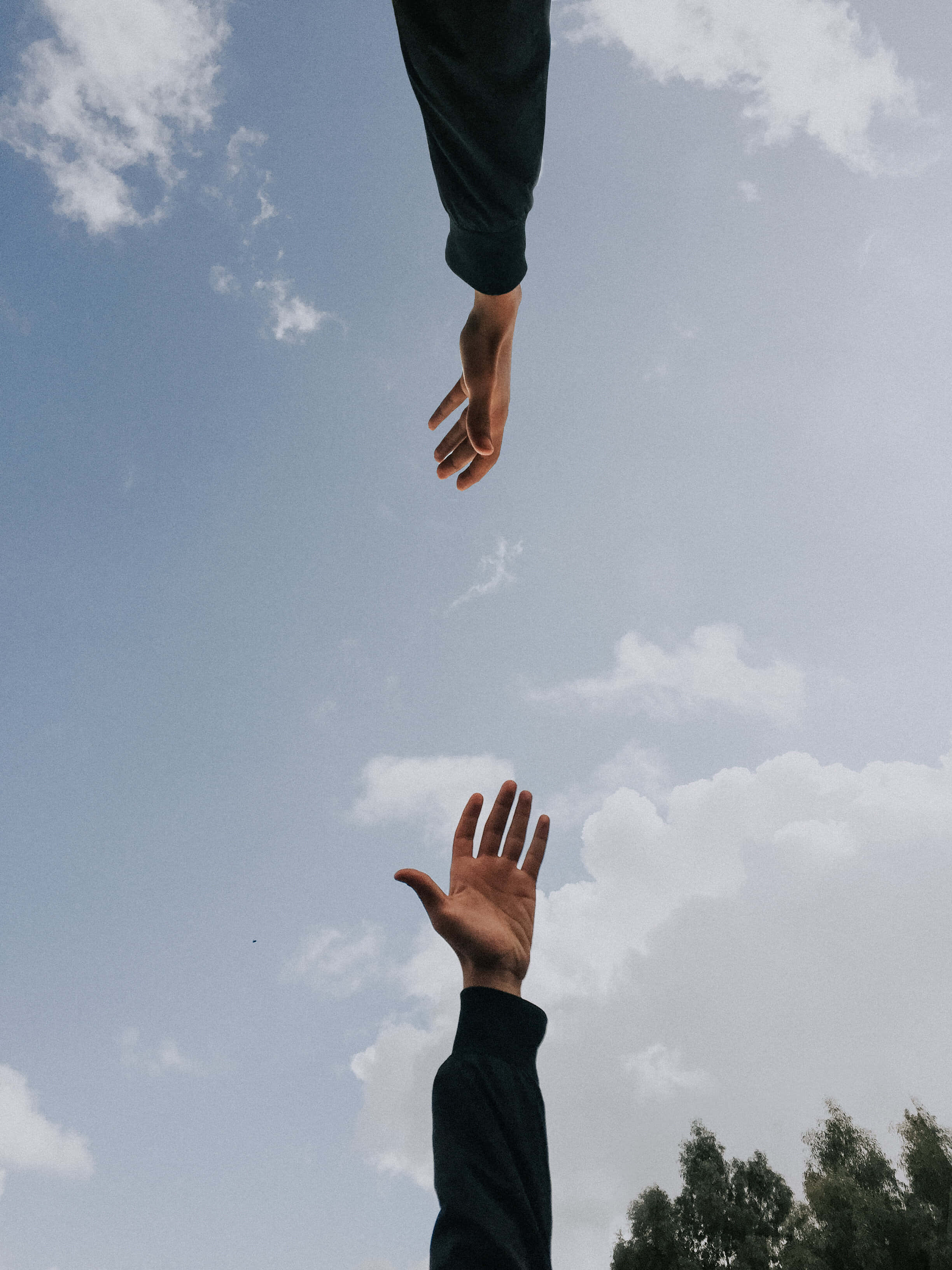 hands up 桌布 壁紙 — 兩隻手在晴朗藍天和零星白雲的背景下互相伸向對方。