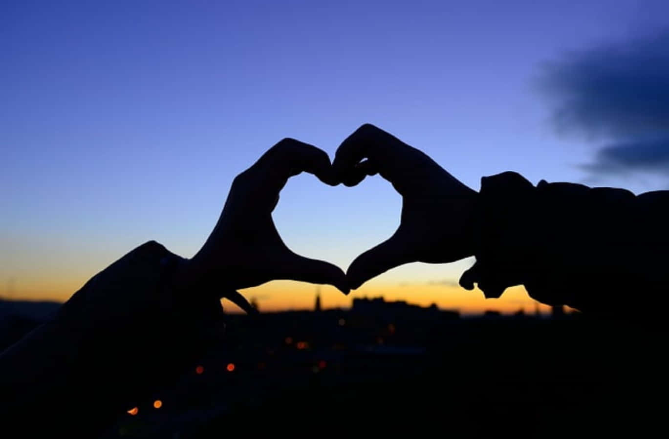 Heart Silhouette 桌布 壁紙 — 兩隻手在暮色天空下形成心形，下方是城市燈光。