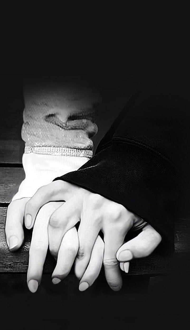 Lovers 桌布 壁紙 — 兩隻手在深色木質表面上以溫柔的黑白肖像緊握在一起。