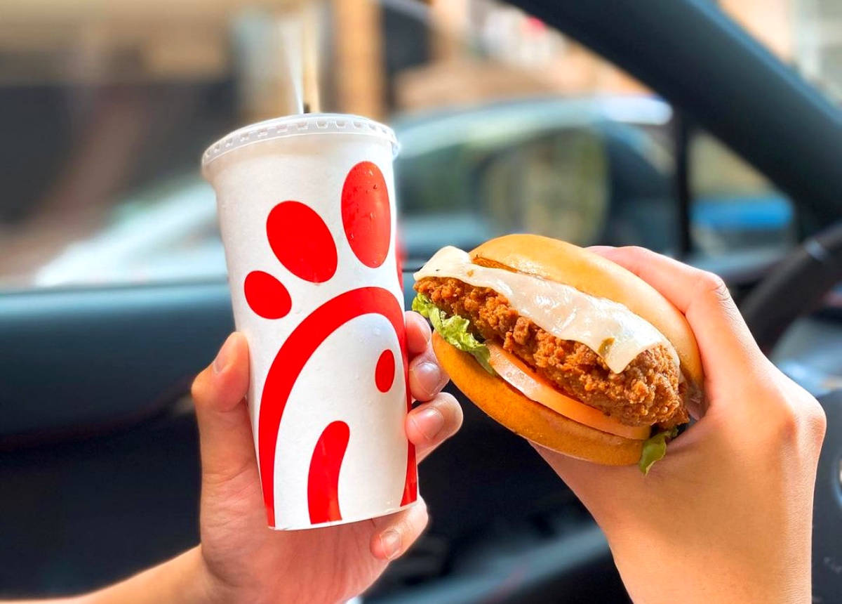 chick 桌布 壁紙 — 兩隻手在白天於車內拿著一份Chick-fil-A雞肉三明治和一杯飲料。