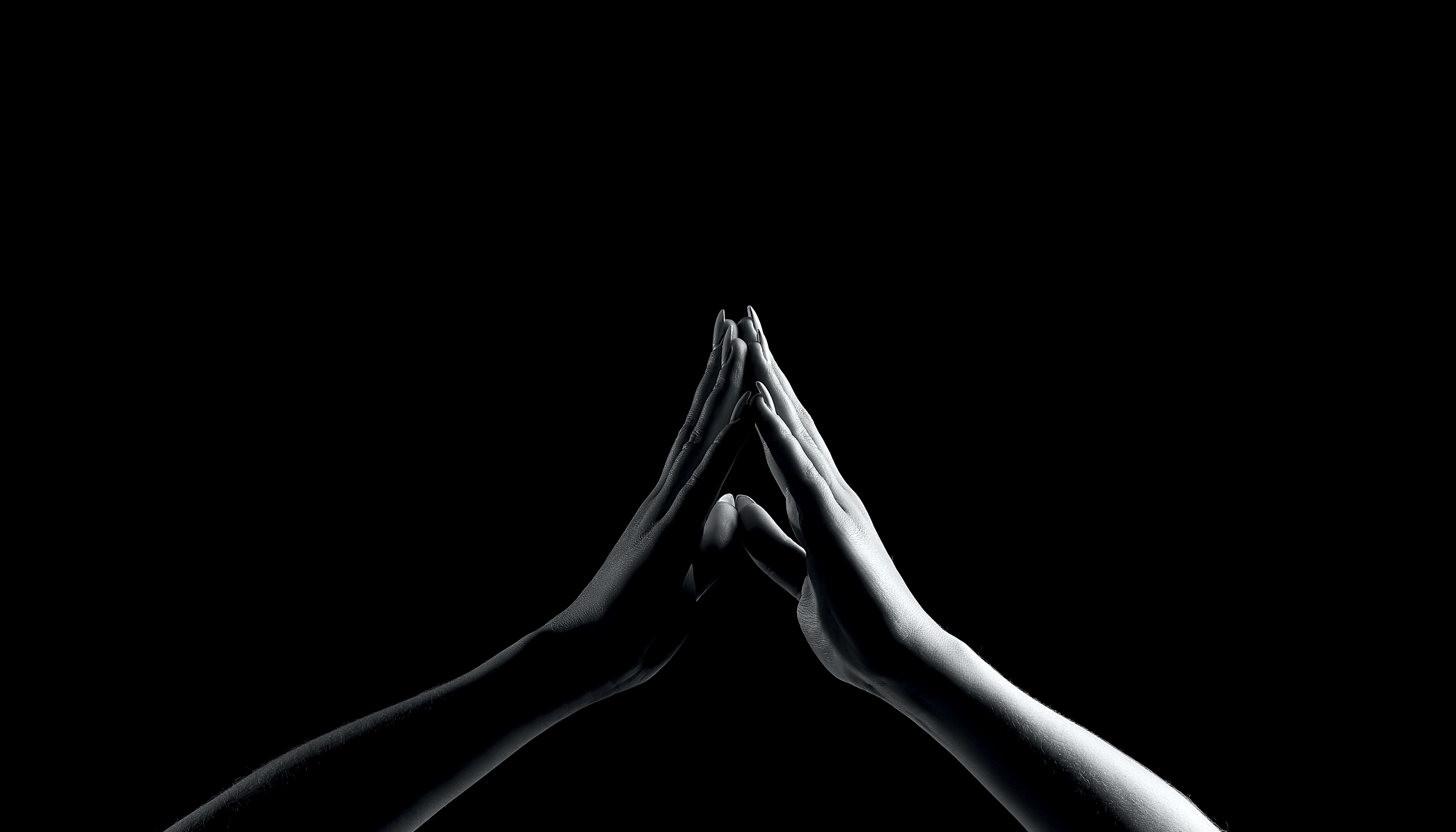 hands 桌布 壁紙 — 兩隻手在祈禱中緊握，背景為 stark 黑色，帶有戲劇性燈光。