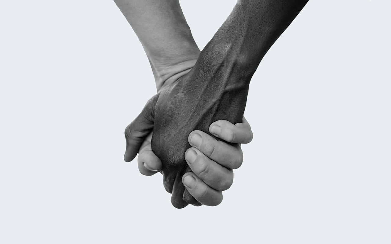 People 桌布 壁紙 — 兩隻手在純色淺色背景上以單色特寫緊緊相握。