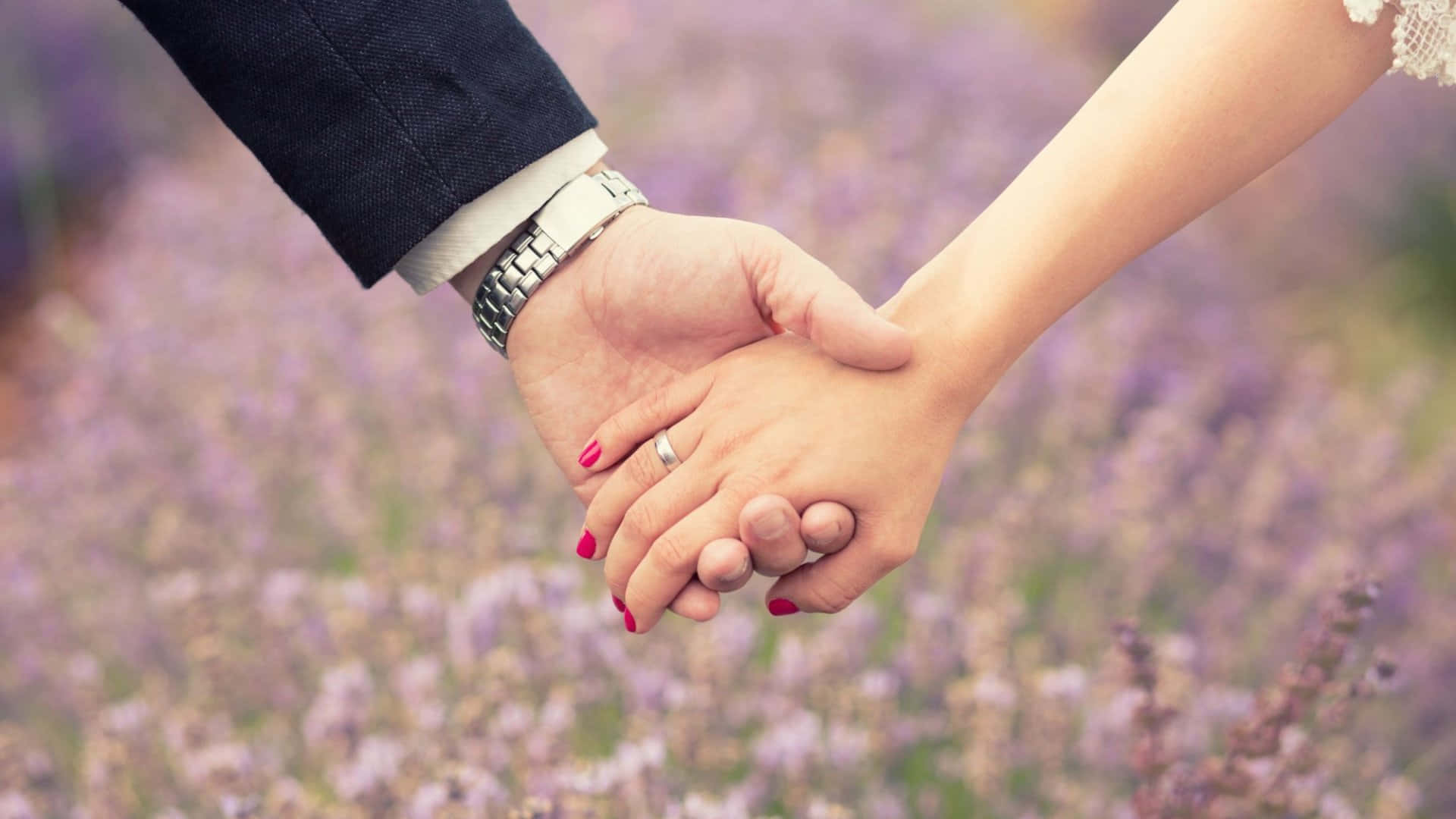 Wedding 桌布 壁紙 — 兩隻手在薰衣草田中緊握，其中一隻戴著結婚戒指和紅色指甲油。