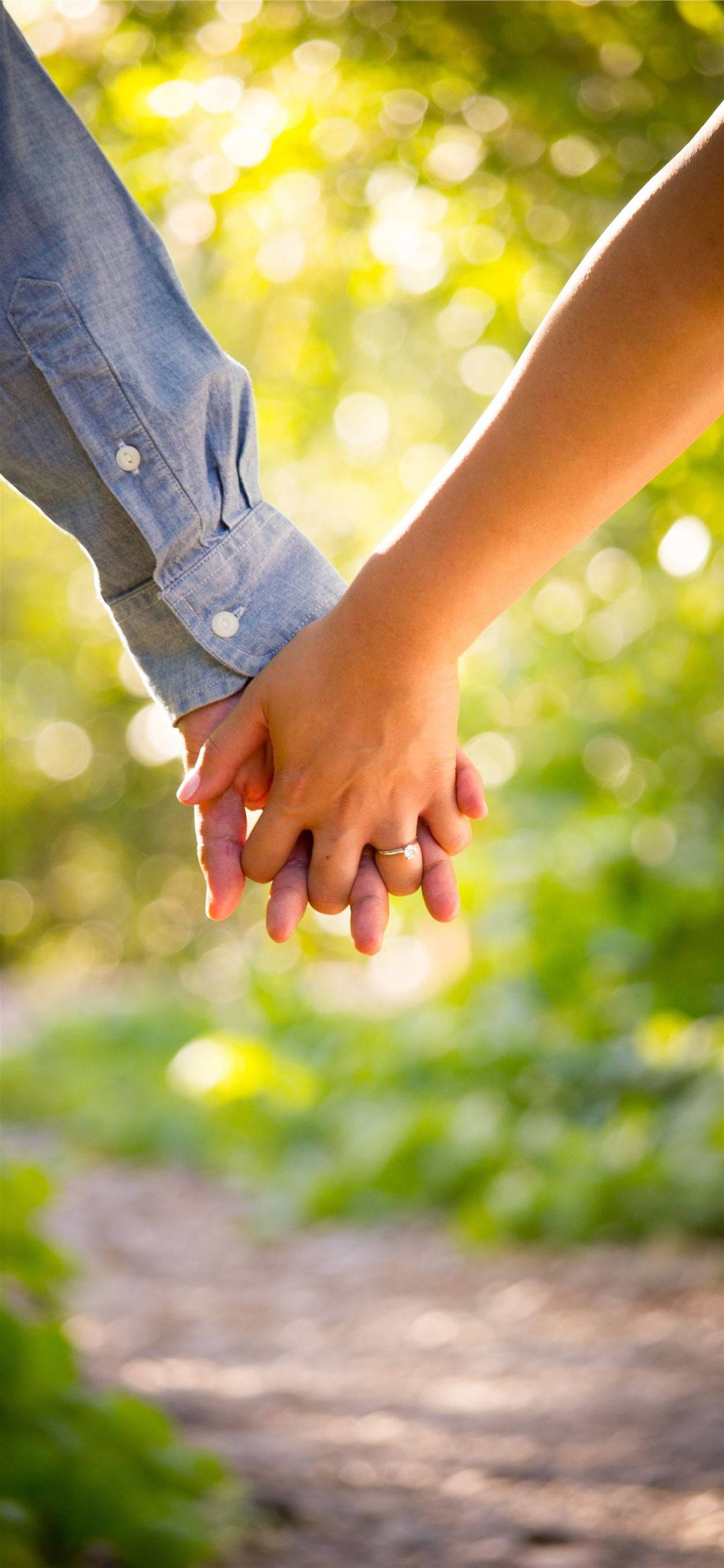 hands 桌布 壁紙 — 兩隻手在陽光普照的花園中緊握在一起，背景是柔和的綠色散景。