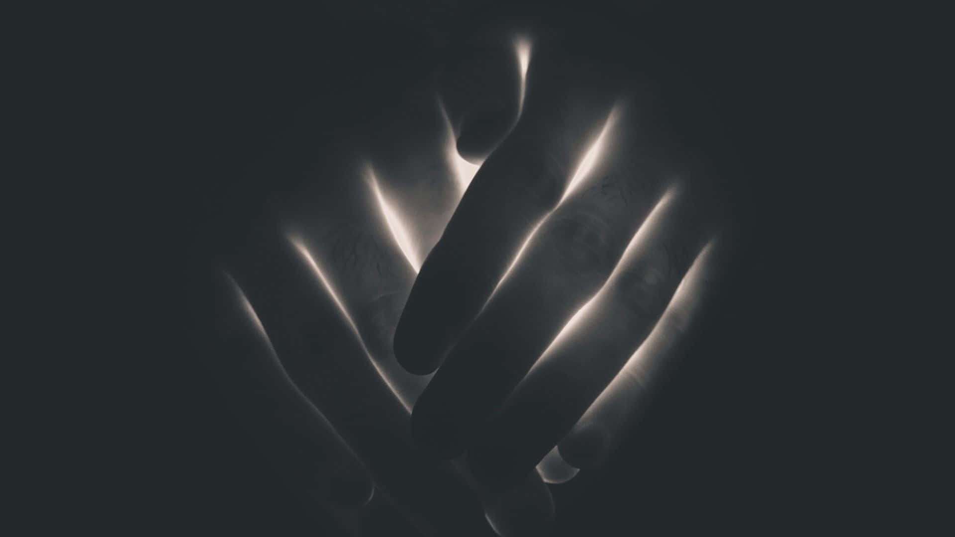 Dark Hand 桌布 壁紙 — 兩隻手在黑暗中緊握，發光的光線描繪手指線條，營造出寧靜親密的時刻。