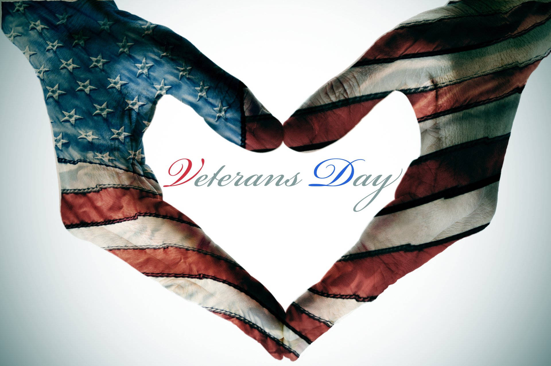 Veterans 桌布 壁紙 — 兩隻手形成心形，帶有美國國旗疊加層，以紀念退伍軍人節，背景為柔和的白色。