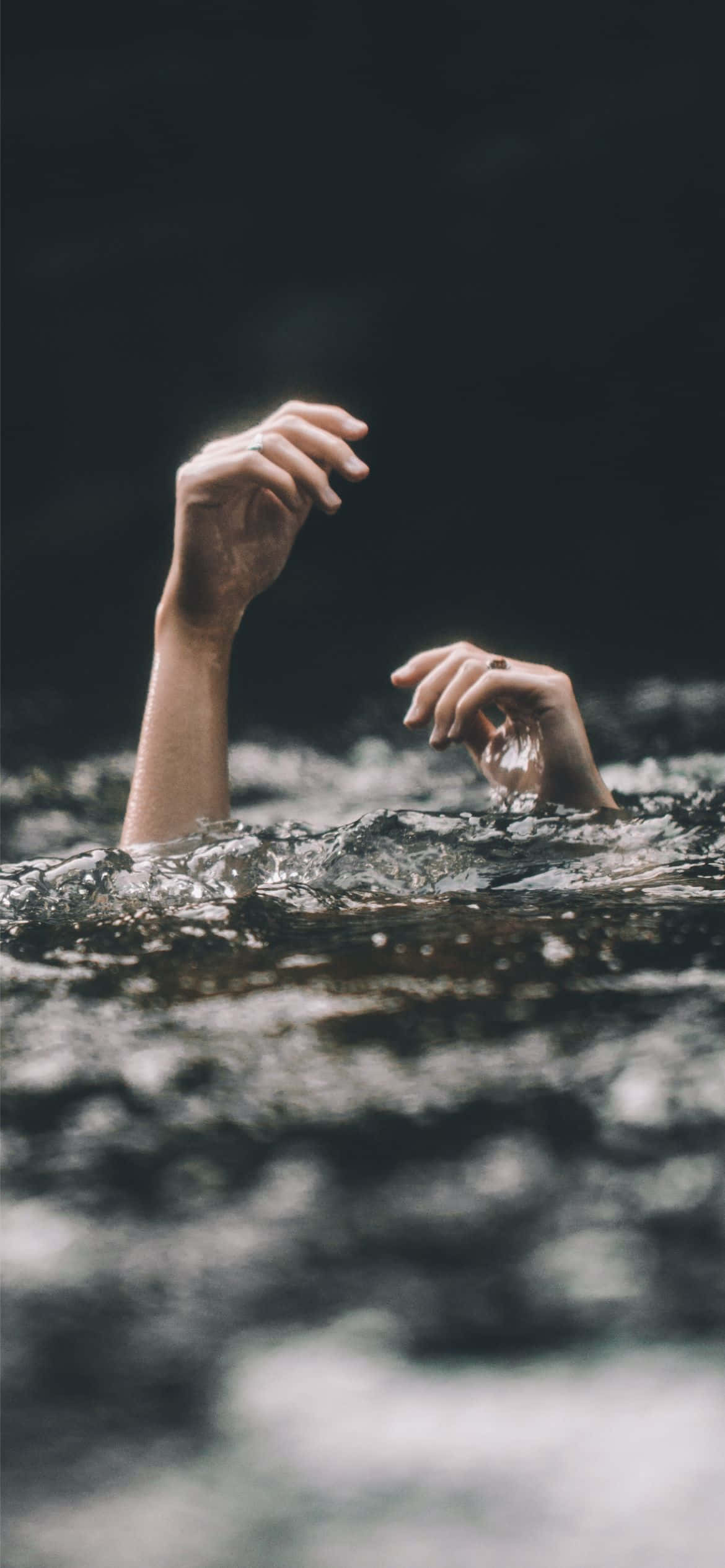 桌布 壁紙 — 兩隻手從黑暗的水中伸出，手指張開抓住水面，水滴落下
