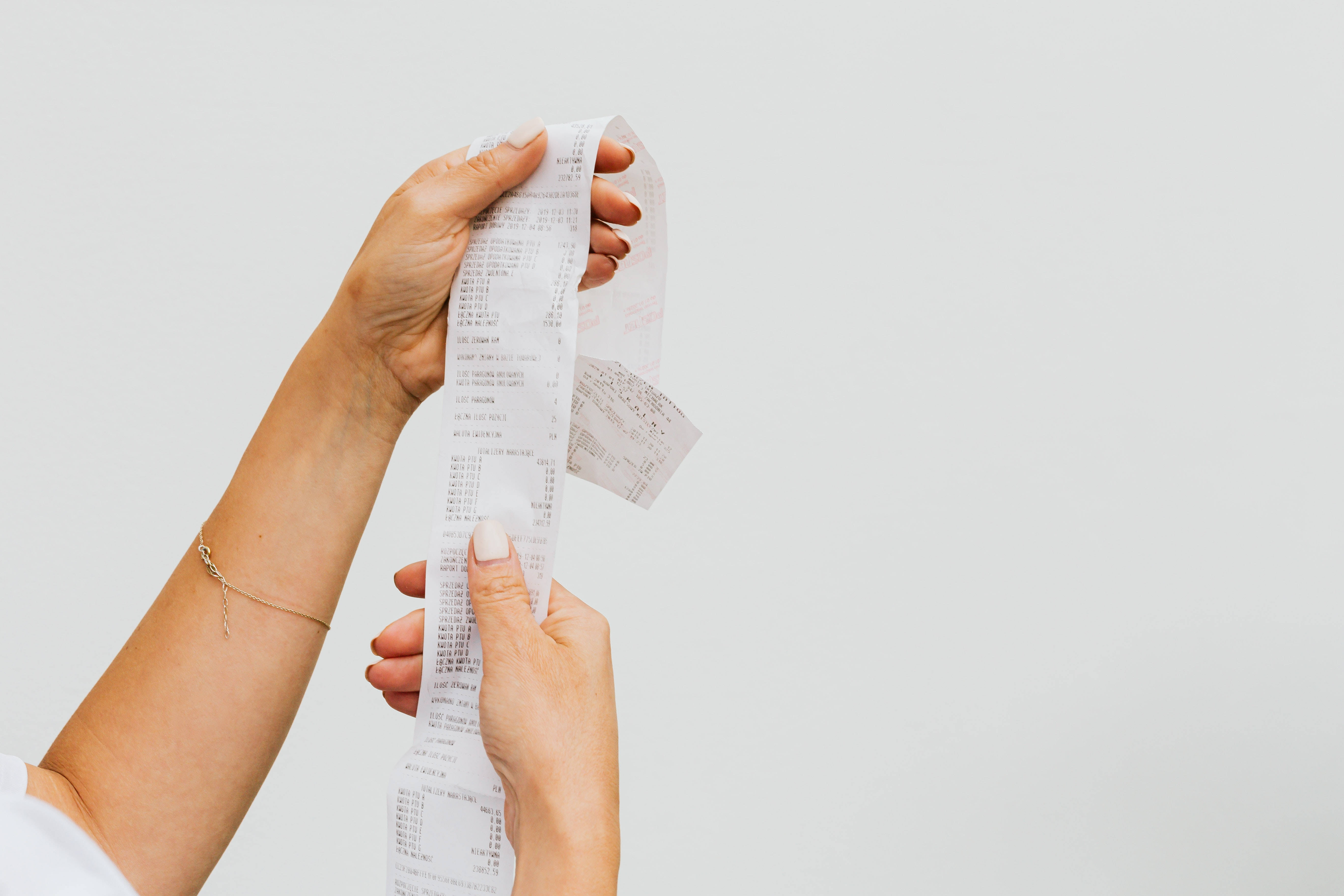paper 桌布 壁紙 — 兩隻手拿著一張長長的列印收據，背景是純淺灰色。
