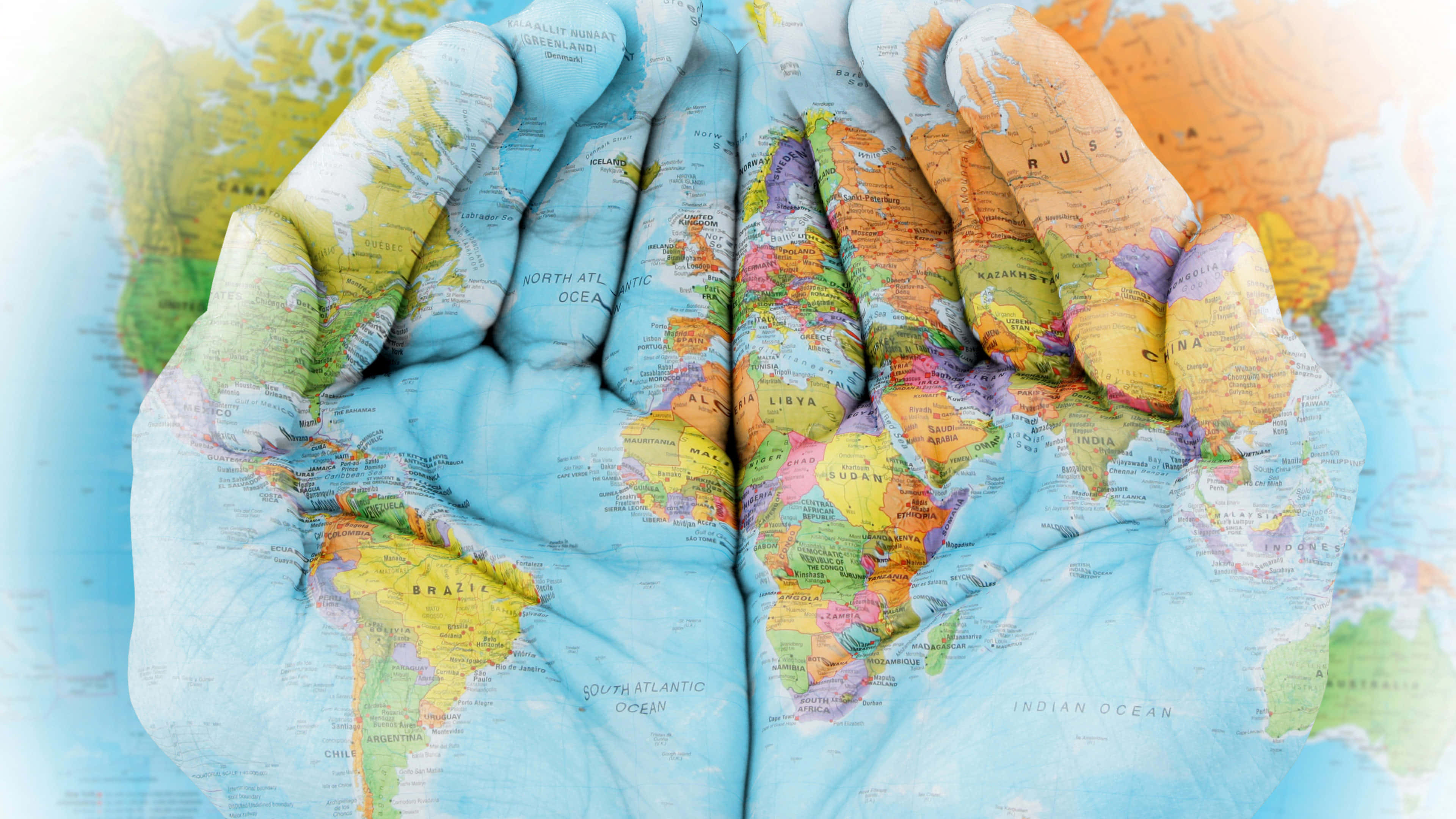 World 桌布 壁紙 — 兩隻手捧著一個世界地圖，手掌和手指上生動地描繪了各大洲和海洋。