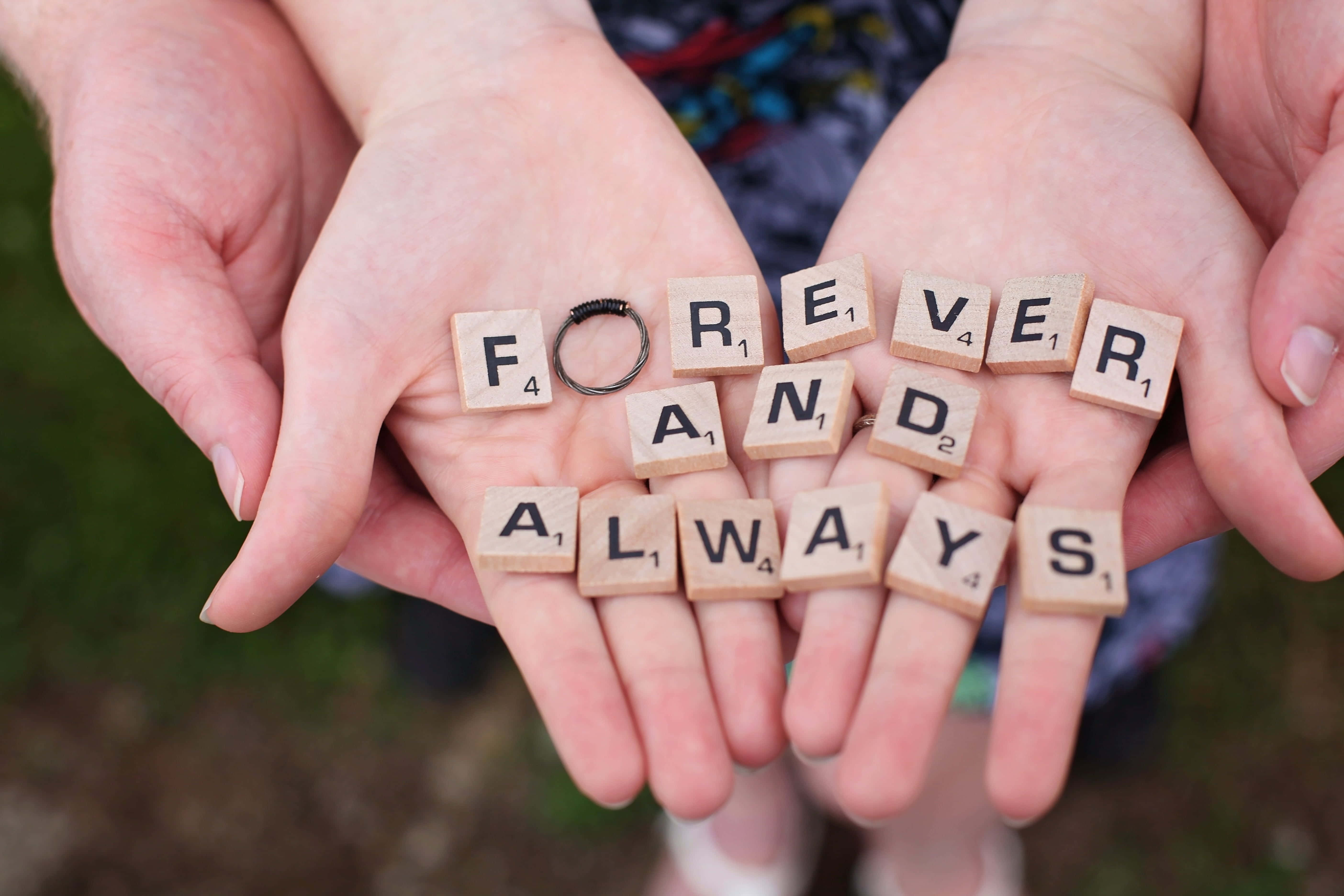child 桌布 壁紙 — 兩隻手捧著木製 Scrabble 字母牌，拼出 forever and always，字母之間放著一枚結婚戒指。