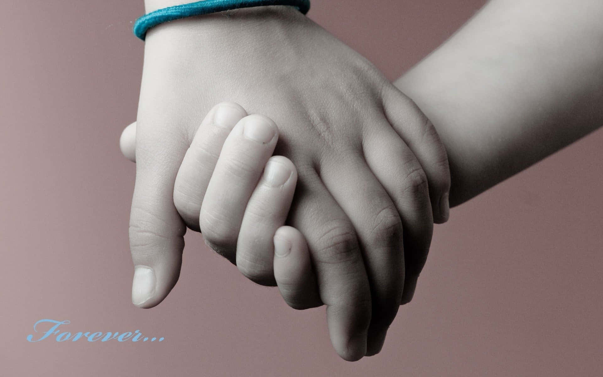 Holding Hands 桌布 壁紙 — 兩隻手溫柔地緊握在一起，背景是柔和粉紅色，配有一個青綠色手鐲和「Forever...」文字。