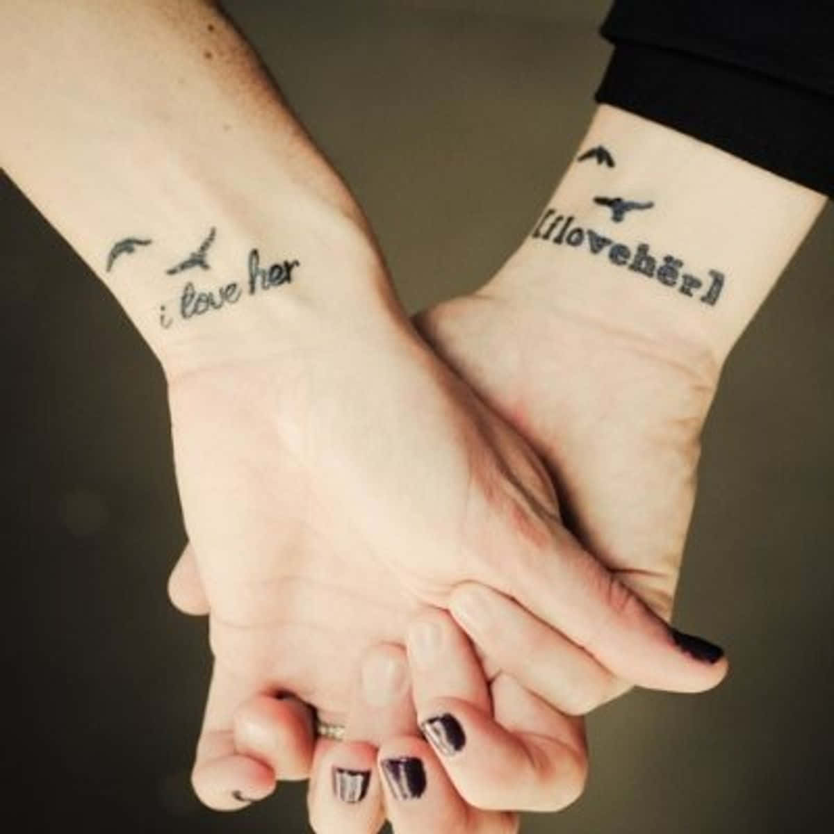 Matching Couple Profile 桌布 壁紙 — 兩隻手緊握在一起，展示匹配的紋身，上面寫著「i love her」和「i love her」，上方有鳥。