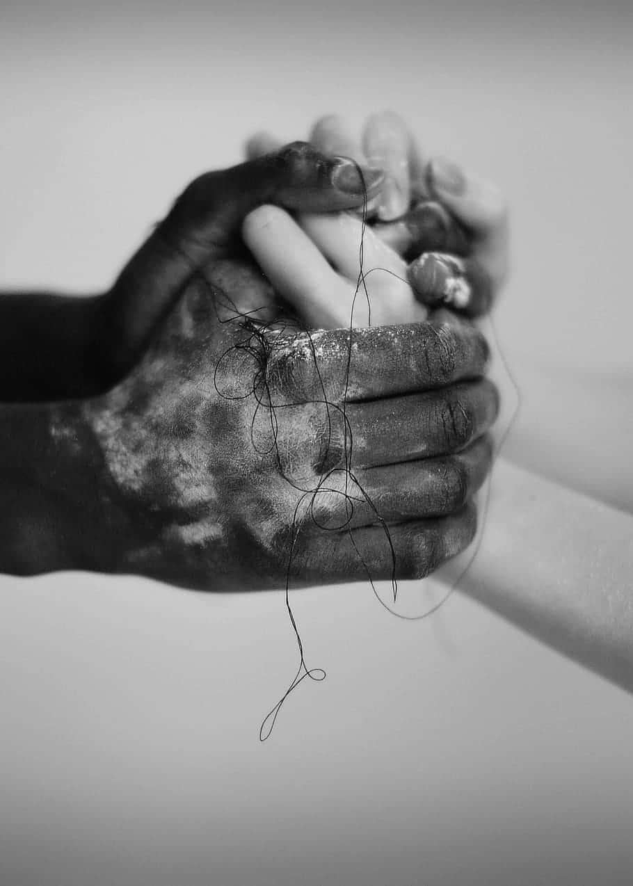Interracial 桌布 壁紙 — 兩隻手緊握在一起的黑白照片，一隻深色有紋理，另一隻蒼白，細線垂在它們之間。