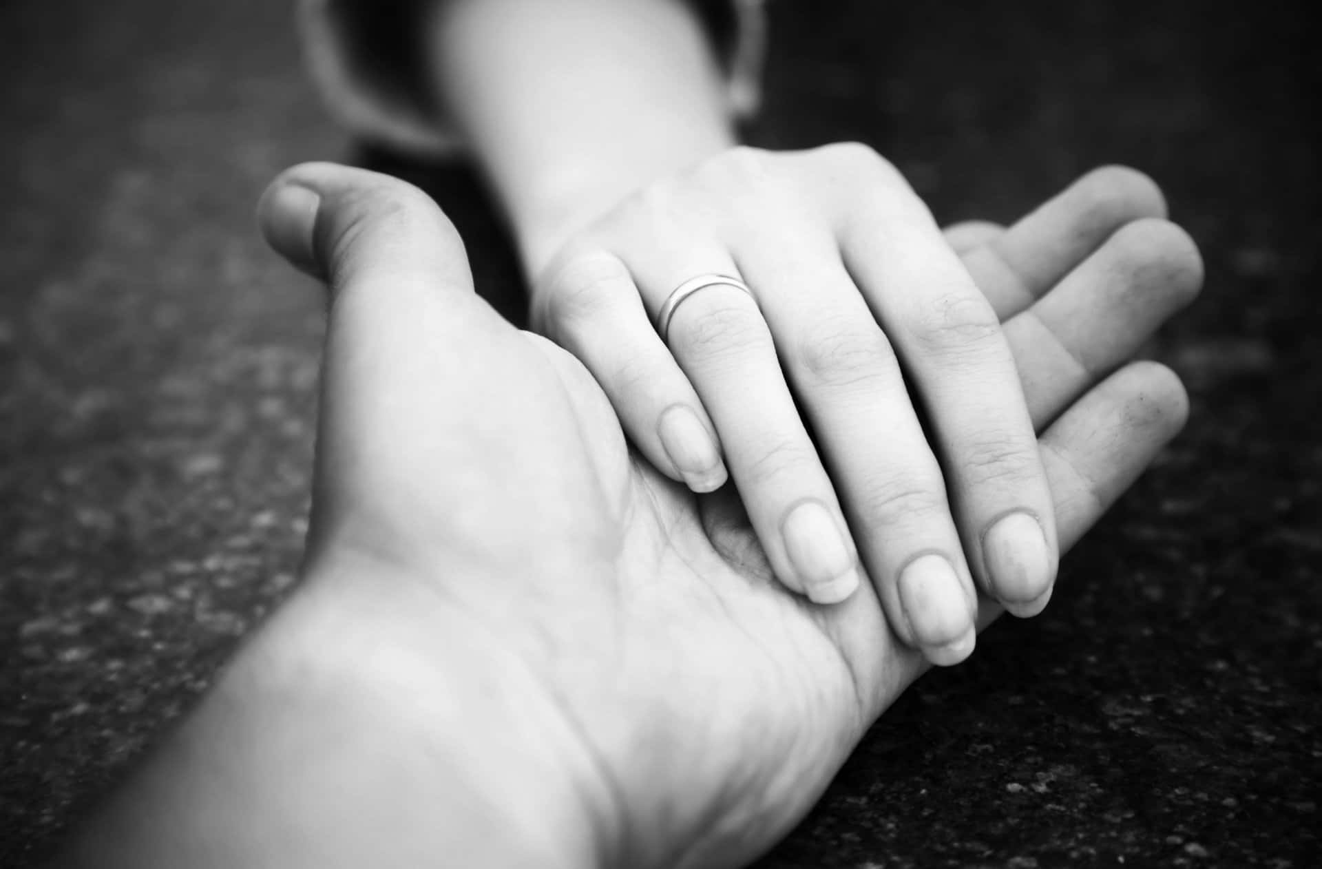 Holding Hands 桌布 壁紙 — 兩隻手緊握在一起的黑白照片，無名指上戴著結婚戒指。