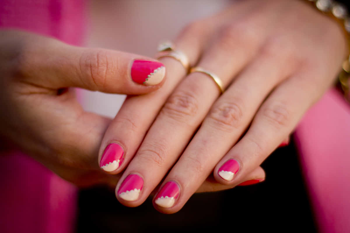 Pink Nails 桌布 壁紙 — 兩隻手緊握的特寫，展示充滿活力的粉紅和白色扇貝形指甲藝術及金戒指。