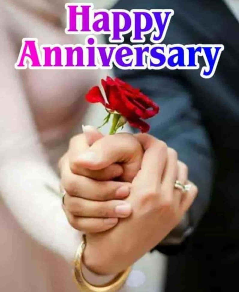 Anniversary 桌布 壁紙 — 兩隻手緊握著一朵紅玫瑰，上方有「Happy Anniversary」文字。