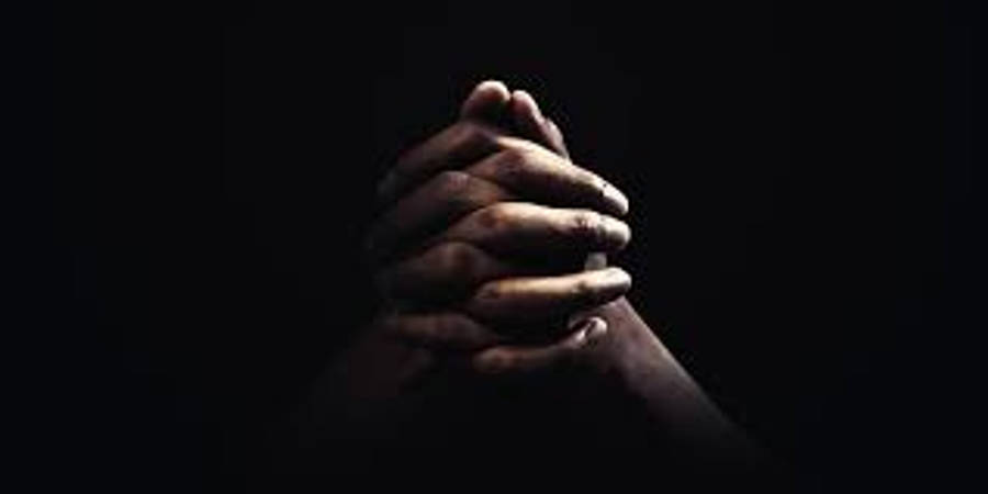 Prayer 桌布 壁紙 — 兩隻手緊緊合十祈禱，背景漆黑如墨，燈光效果戲劇性十足。