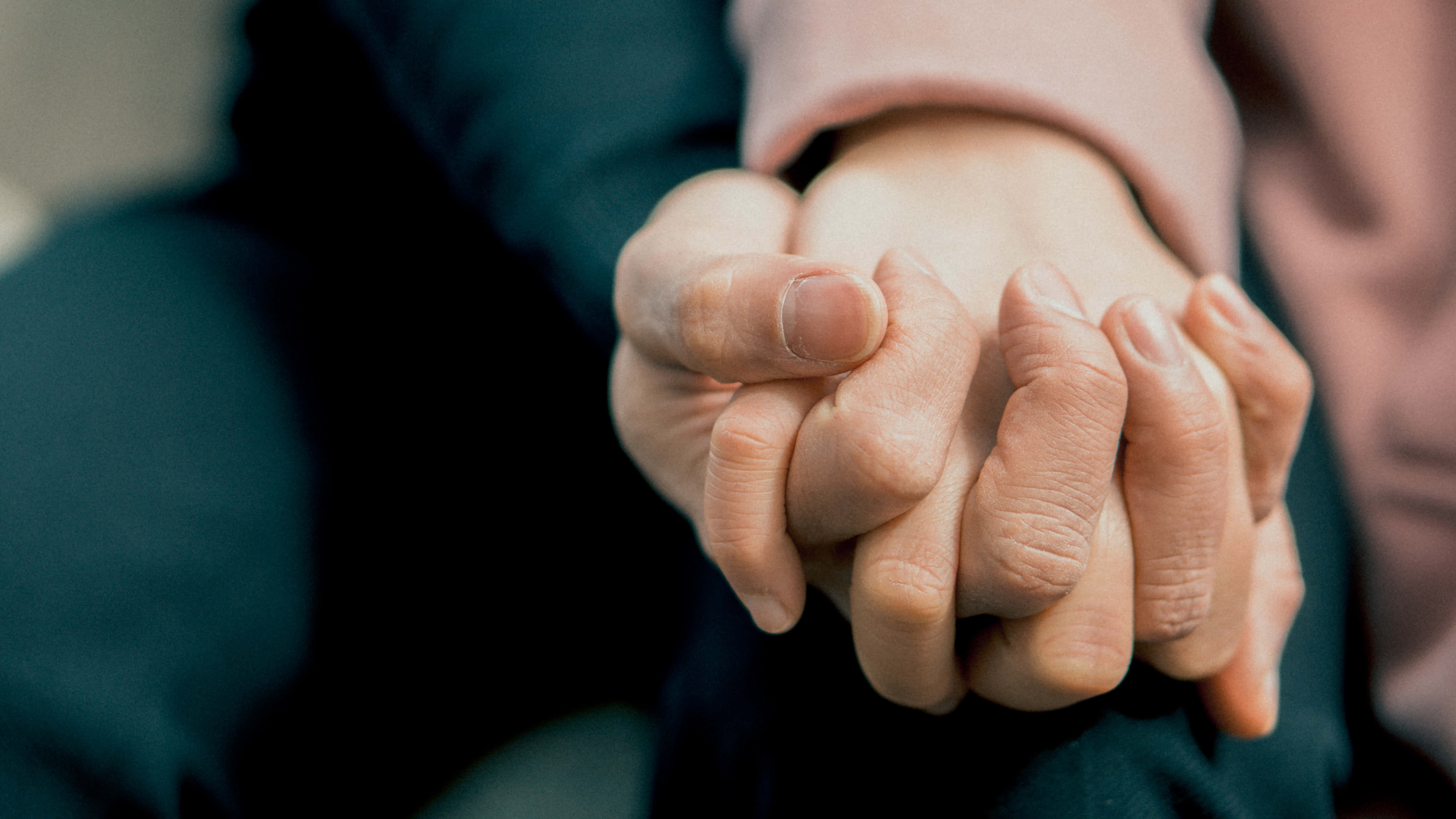 hands 桌布 壁紙 — 兩隻手緊緊握在一起，以溫柔的姿態傳達安慰與支持，背景柔和模糊。