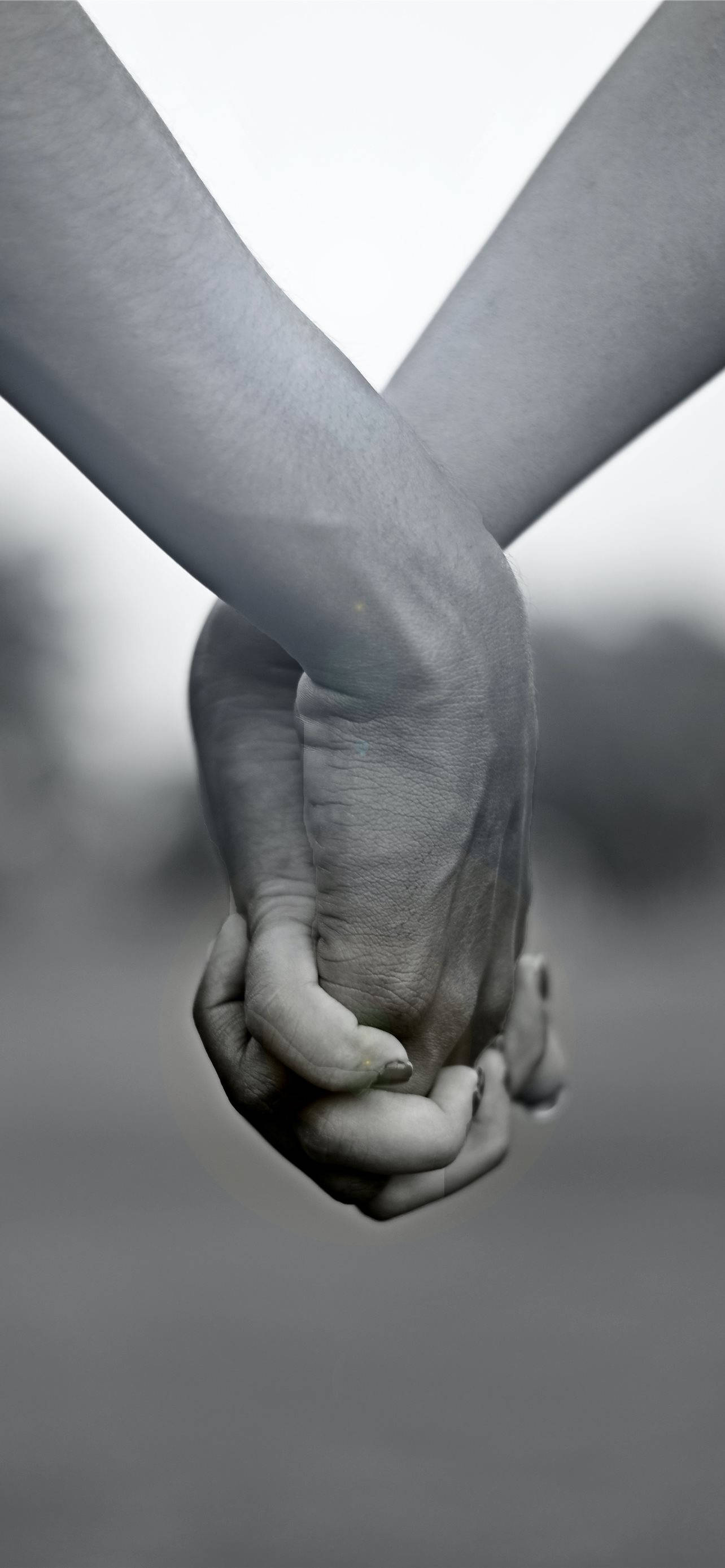 hands 桌布 壁紙 — 兩隻手緊緊握在一起，在模糊背景下的單色特寫。