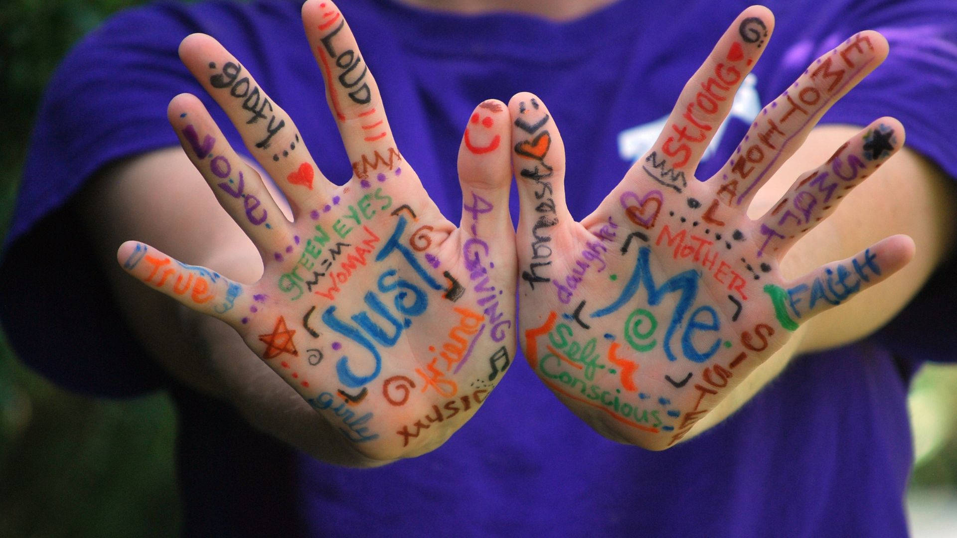 藝術 桌布 壁紙 — 兩隻手覆蓋著色彩繽紛的詞語，例如「Just Me」和「Strong」，向前伸出，背景是模糊的綠色。