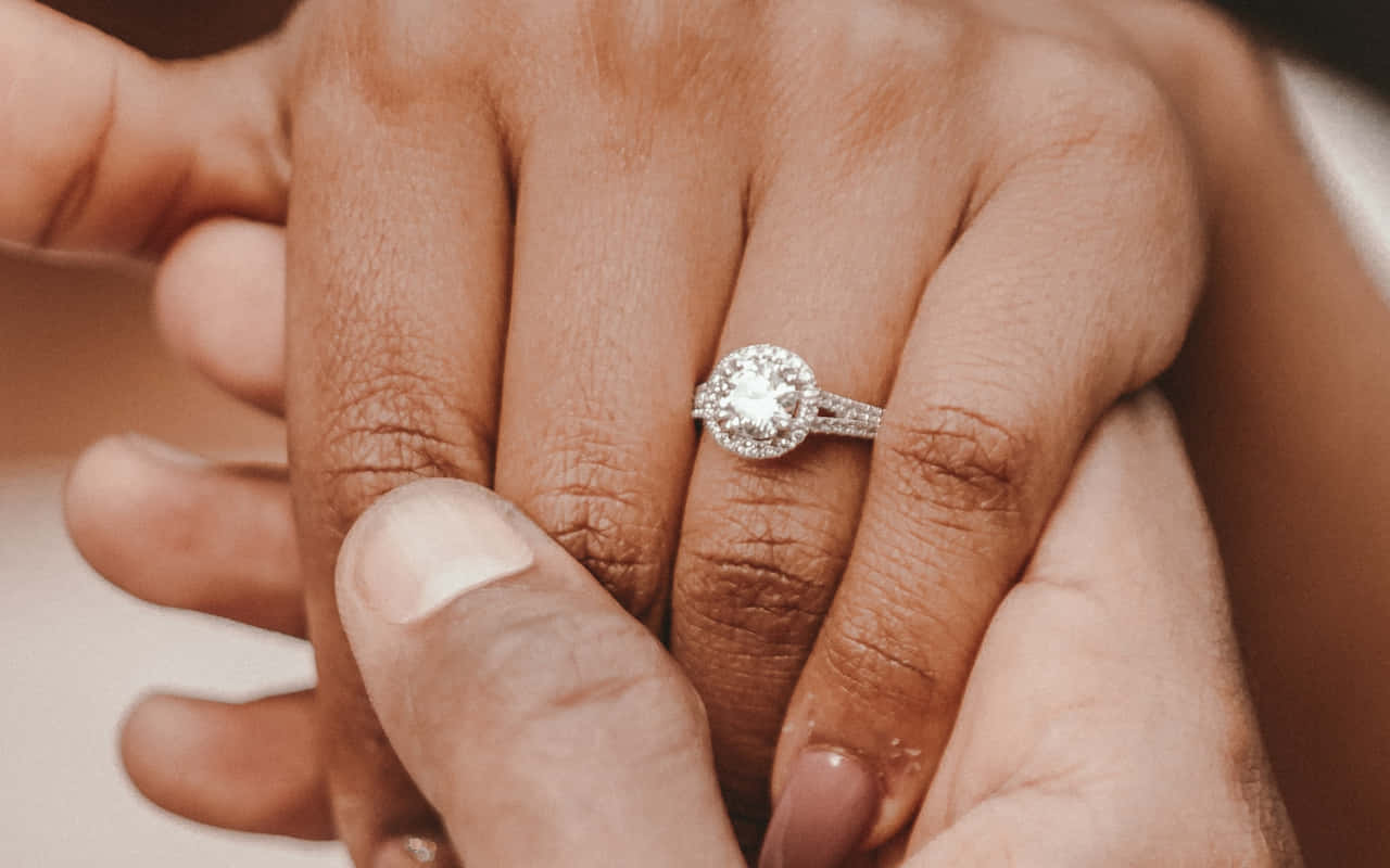 Marriage 桌布 壁紙 — 兩隻手輕輕交握的特寫，無名指上戴著閃閃發光的鑽石訂婚戒指。