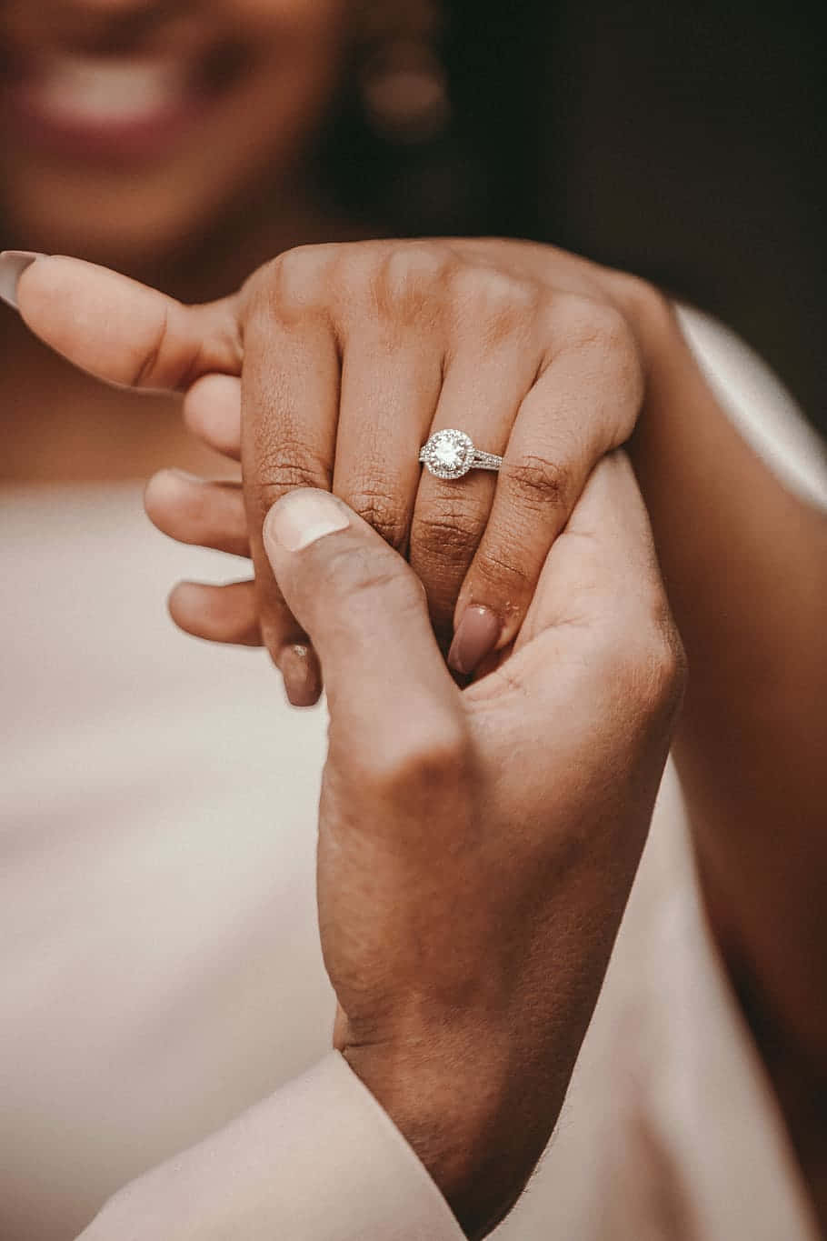 Holding Hands 桌布 壁紙 — 兩隻手輕輕交握的特寫，無名指上戴著一枚閃閃發光的鑽石訂婚戒指。