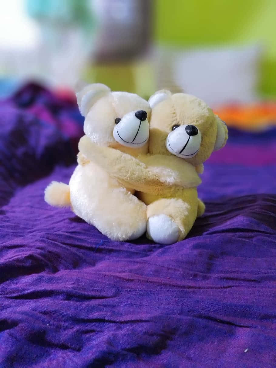 Cute Love 桌布 壁紙 — 兩隻毛絨泰迪熊在皺巴巴的紫色布料上緊緊擁抱，背景是色彩繽紛的模糊效果。