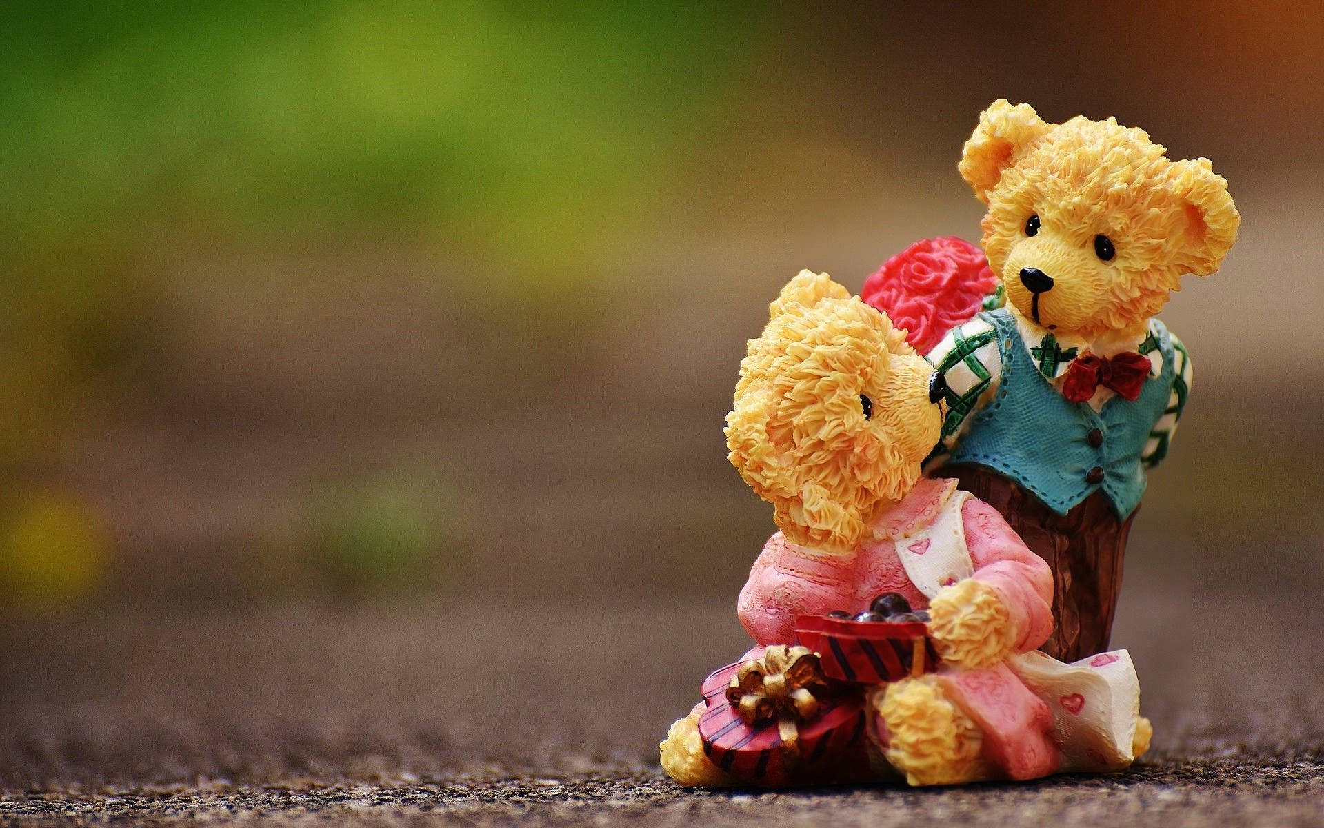 Teddy Bear 桌布 壁紙 — 兩隻毛茸茸的泰迪熊相愛坐在一起，一隻拿著紅玫瑰，另一隻拿著禮物盒，在紋理地面上。