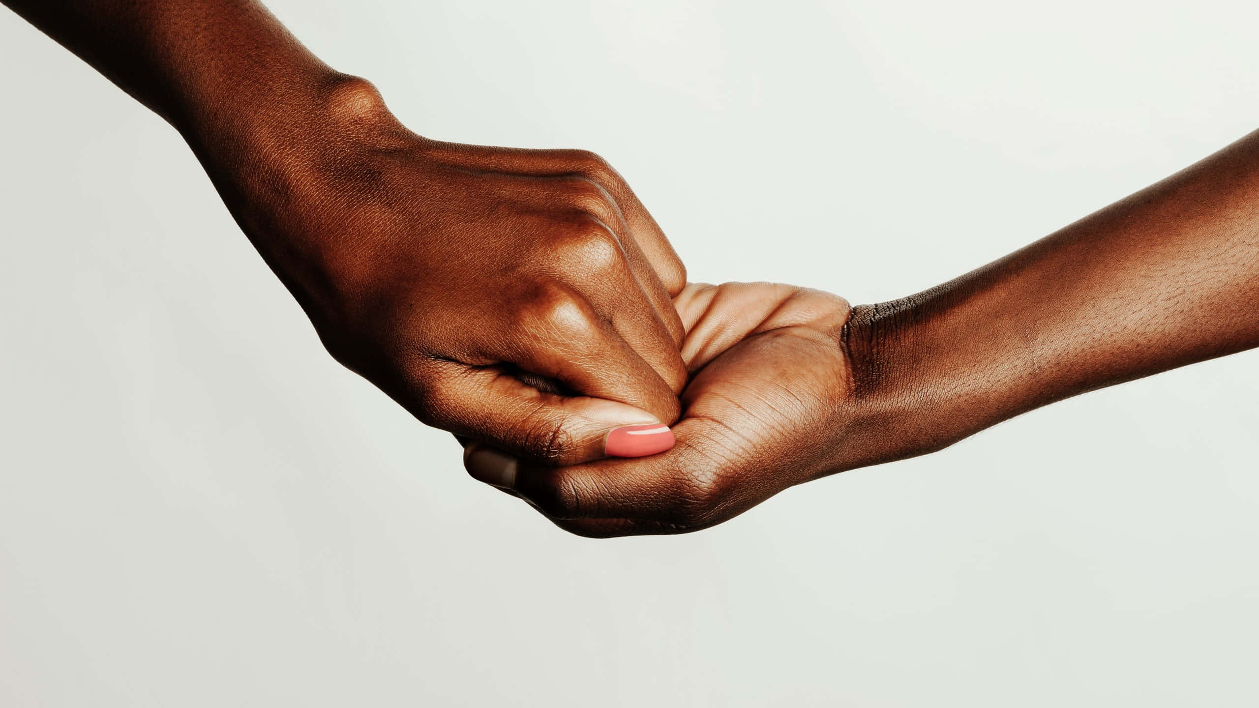 relationship love 桌布 壁紙 — 兩隻深色皮膚的手輕輕交握，背景為柔和的白色，傳達團結與支持。