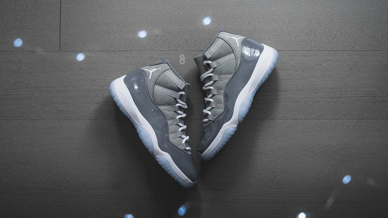 Cool Grey 桌布 壁紙 — 兩隻灰色Jordan 11運動鞋在深色木地板上排列成心形，伴隨發光藍色散景燈光。