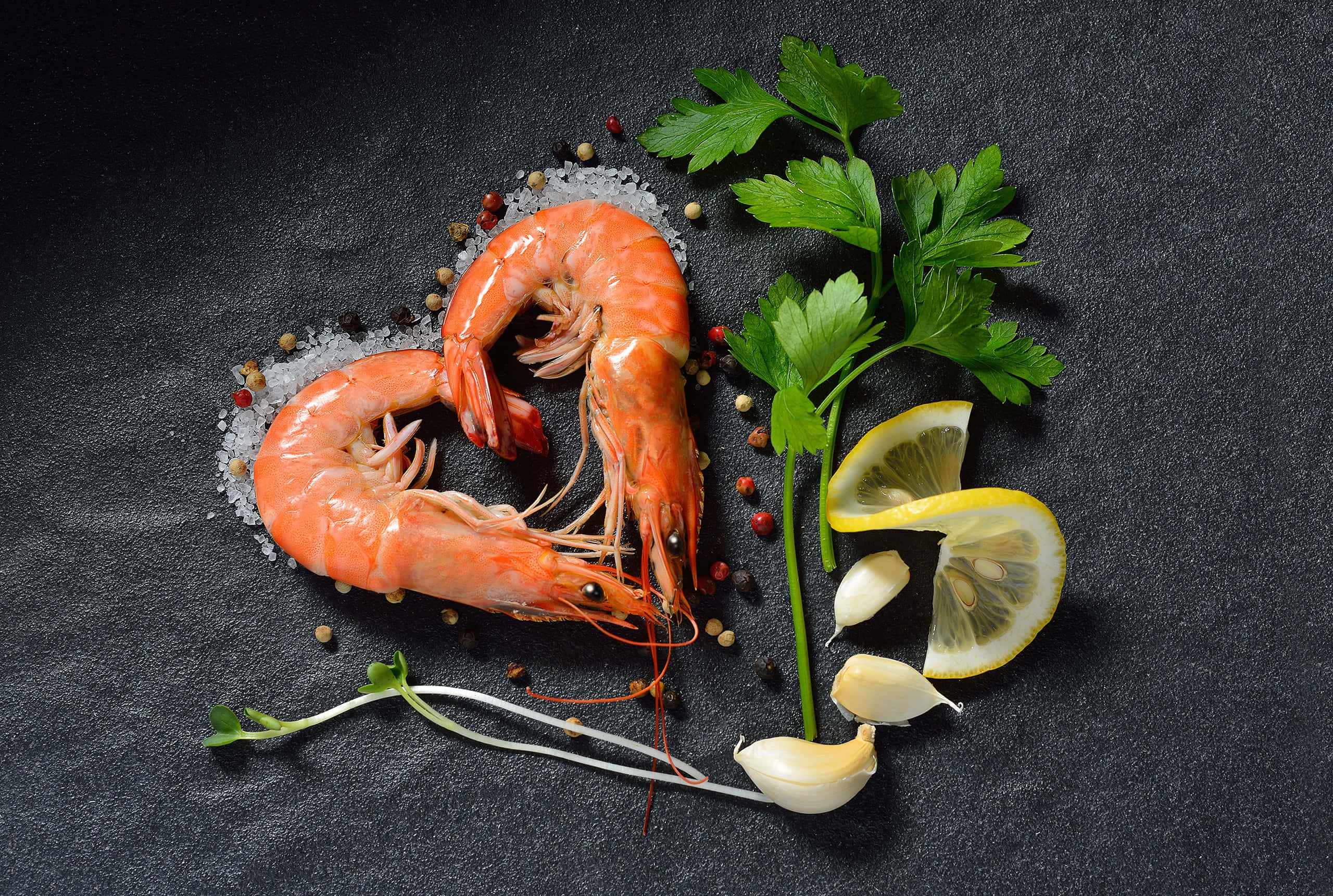 shrimp 桌布 壁紙 — 兩隻煮熟的蝦在鹽上形成心形，搭配歐芹、檸檬和大蒜，放在深色石板上。