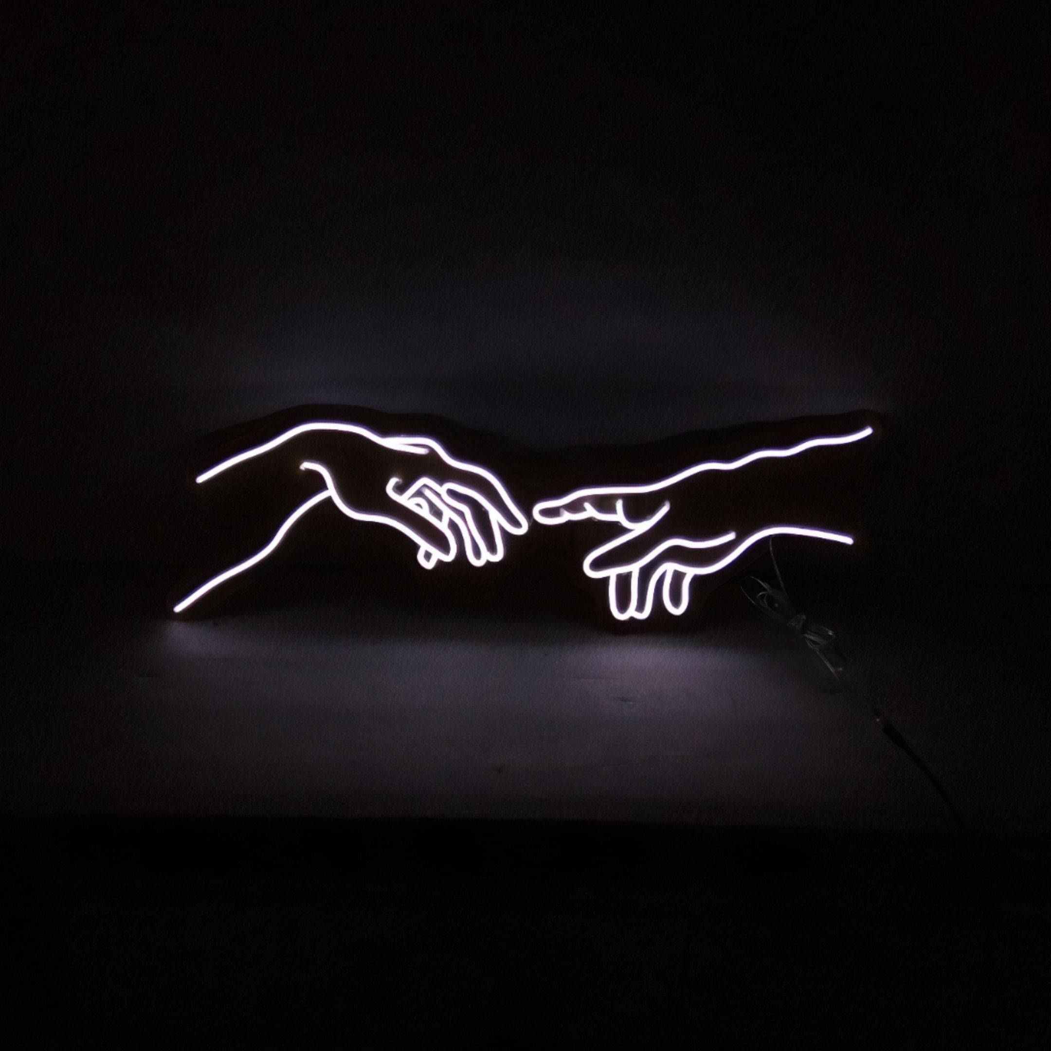 lights 桌布 壁紙 — 兩隻發光的白色霓虹燈手在黑暗背景前互相伸向對方，構成極簡主義藝術作品。