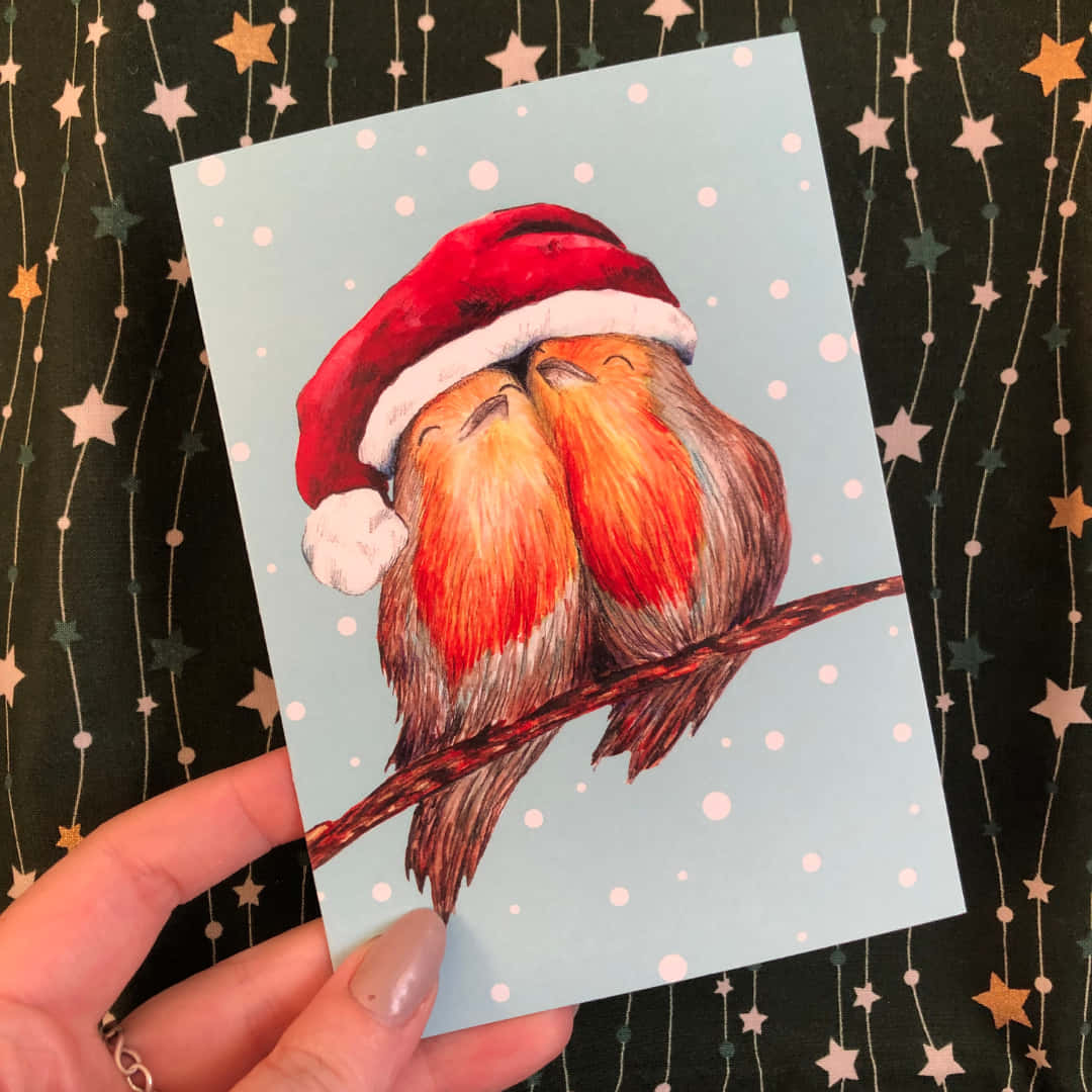 節日 桌布 壁紙 — 兩隻睡眼惺忪的鳥兒戴著紅色聖誕帽，在雪花紛飛的星空背景下依偎在樹枝上。