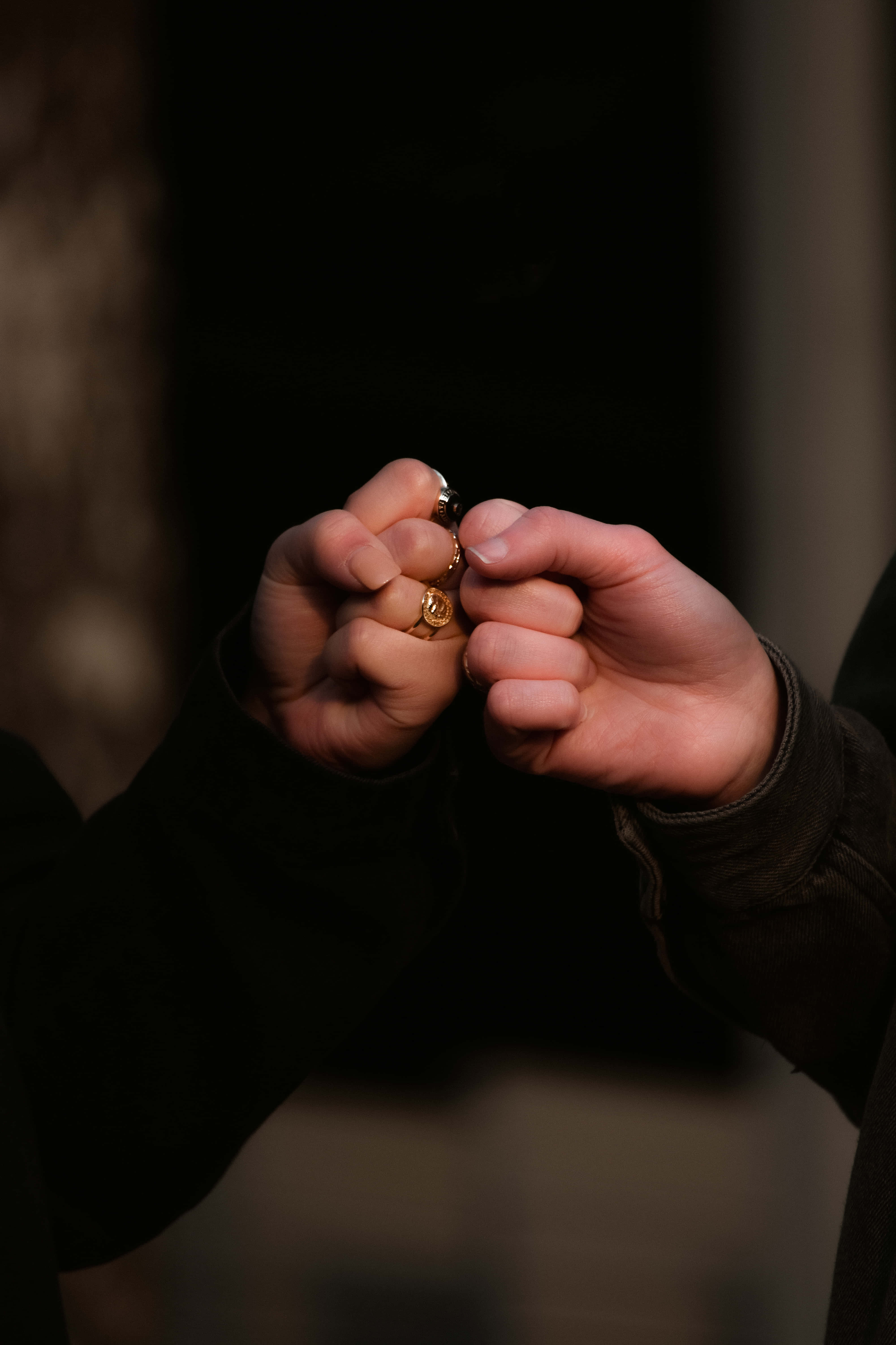 桌布 壁紙 — 兩隻穿著深色衣服的手在黑色背景前緊握一個小金黃色物體。