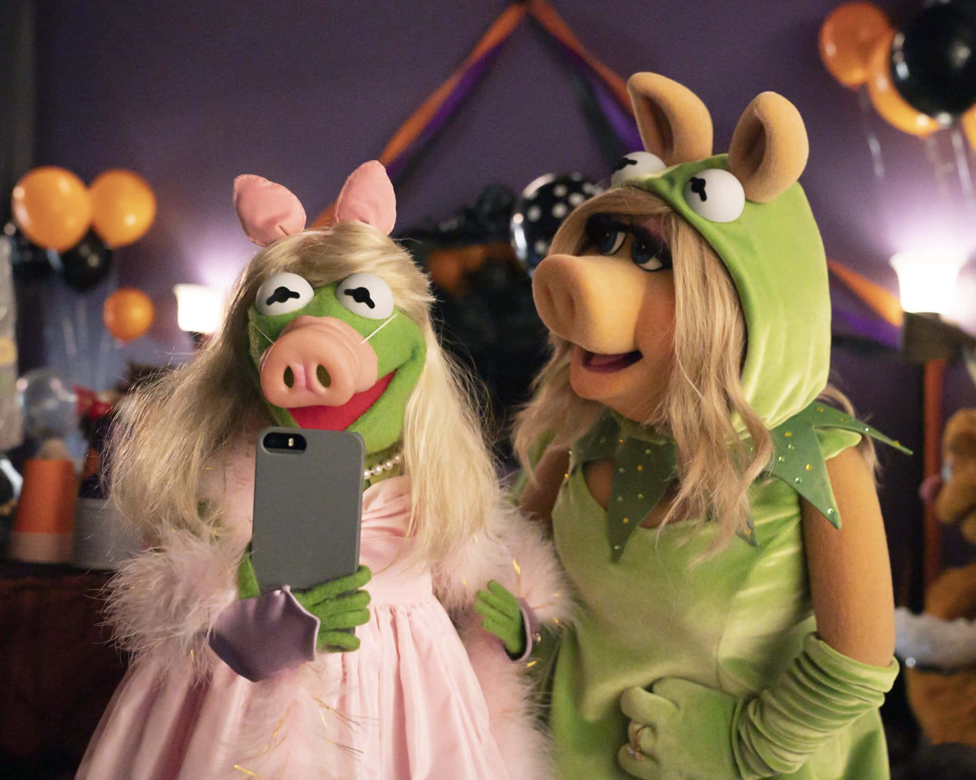 Cool Piggy 桌布 壁紙 — 兩隻穿著萬聖節服裝的Muppet豬在一個有氣球和燈光的節日派對上自拍。