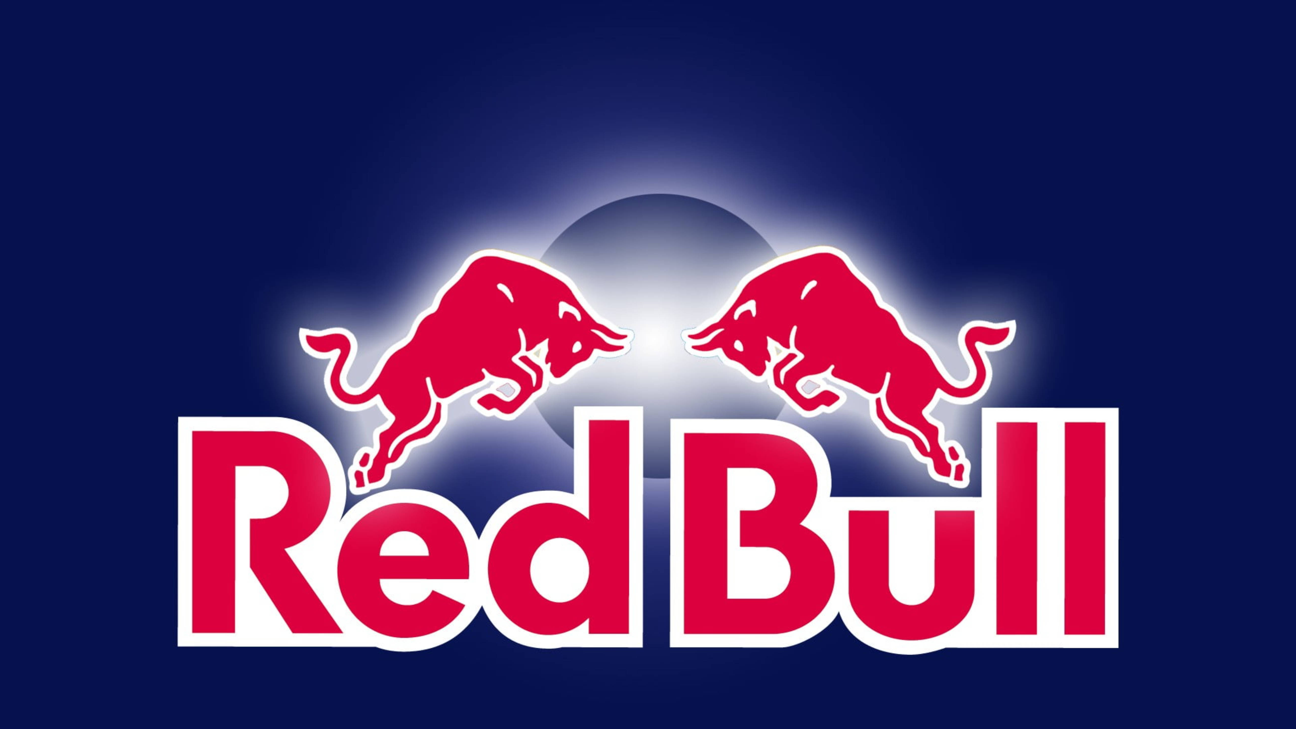 bull 桌布 壁紙 — 兩隻紅色衝鋒的公牛在深藍色背景上跳躍，帶有發光的白色光環和粗體紅色「Red Bull」文字。