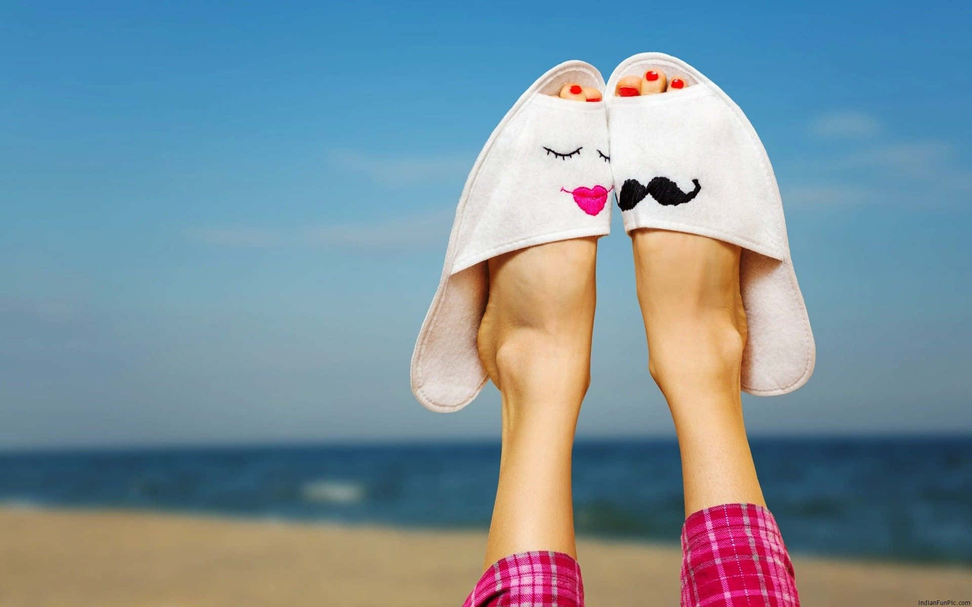 Funny Love 桌布 壁紙 — 兩隻腳穿著可愛的兔子拖鞋，上面有臉，一隻有嘴唇，一隻有鬍子，在陽光明媚的海灘上放鬆。